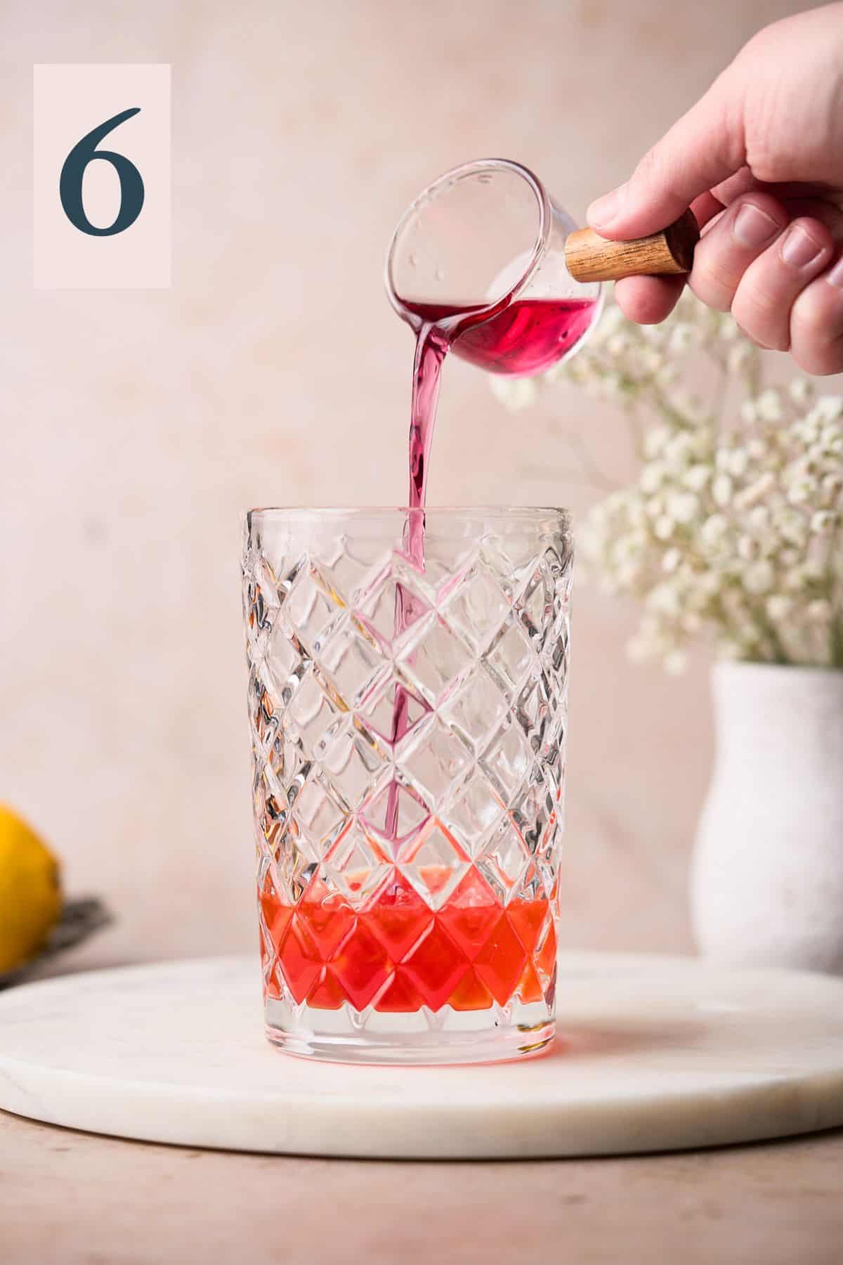 hand pouring pink gin into a cocktail shaker. 