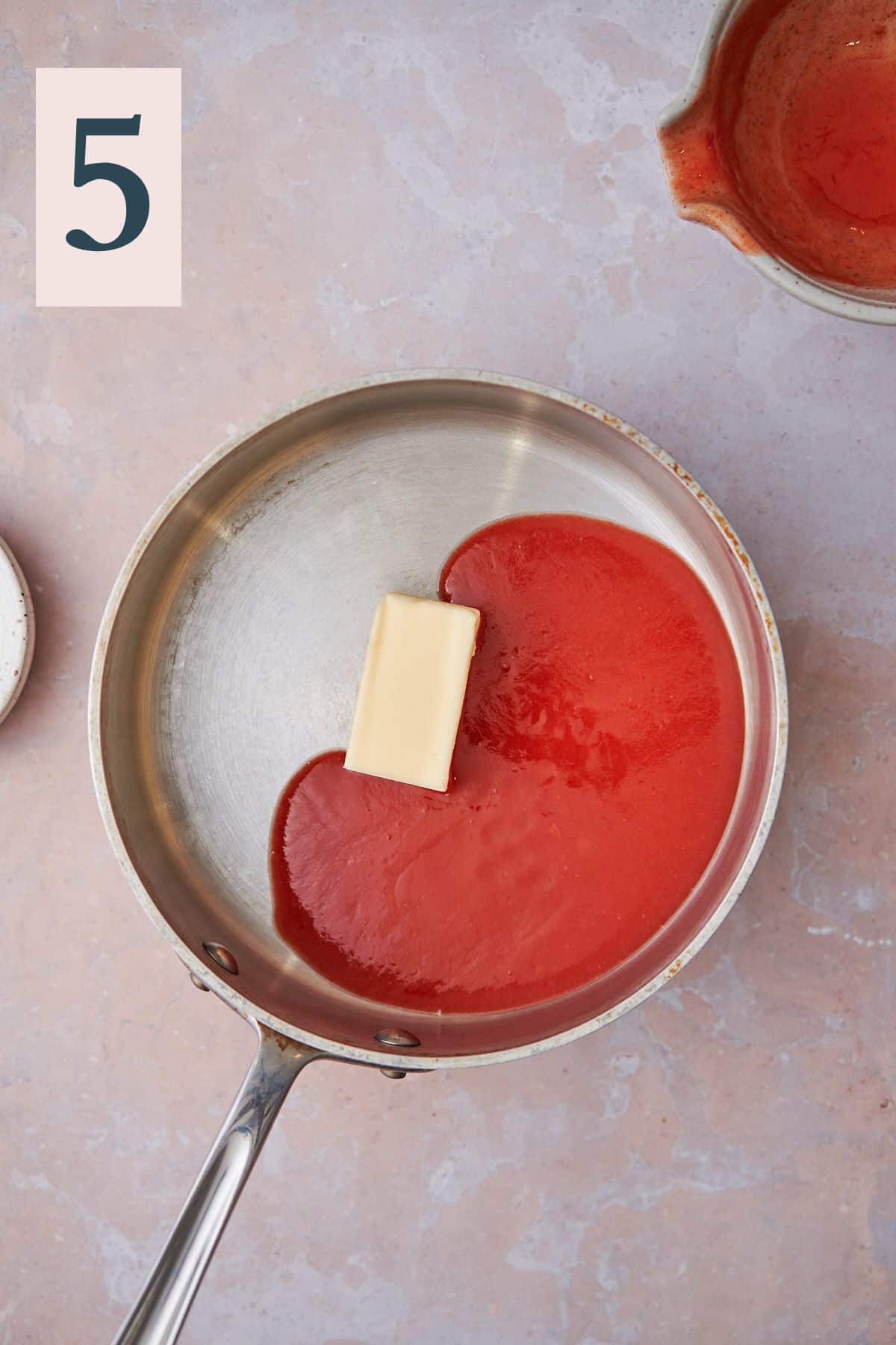 Buffalo sauce with butter melting inside of a saucepan.