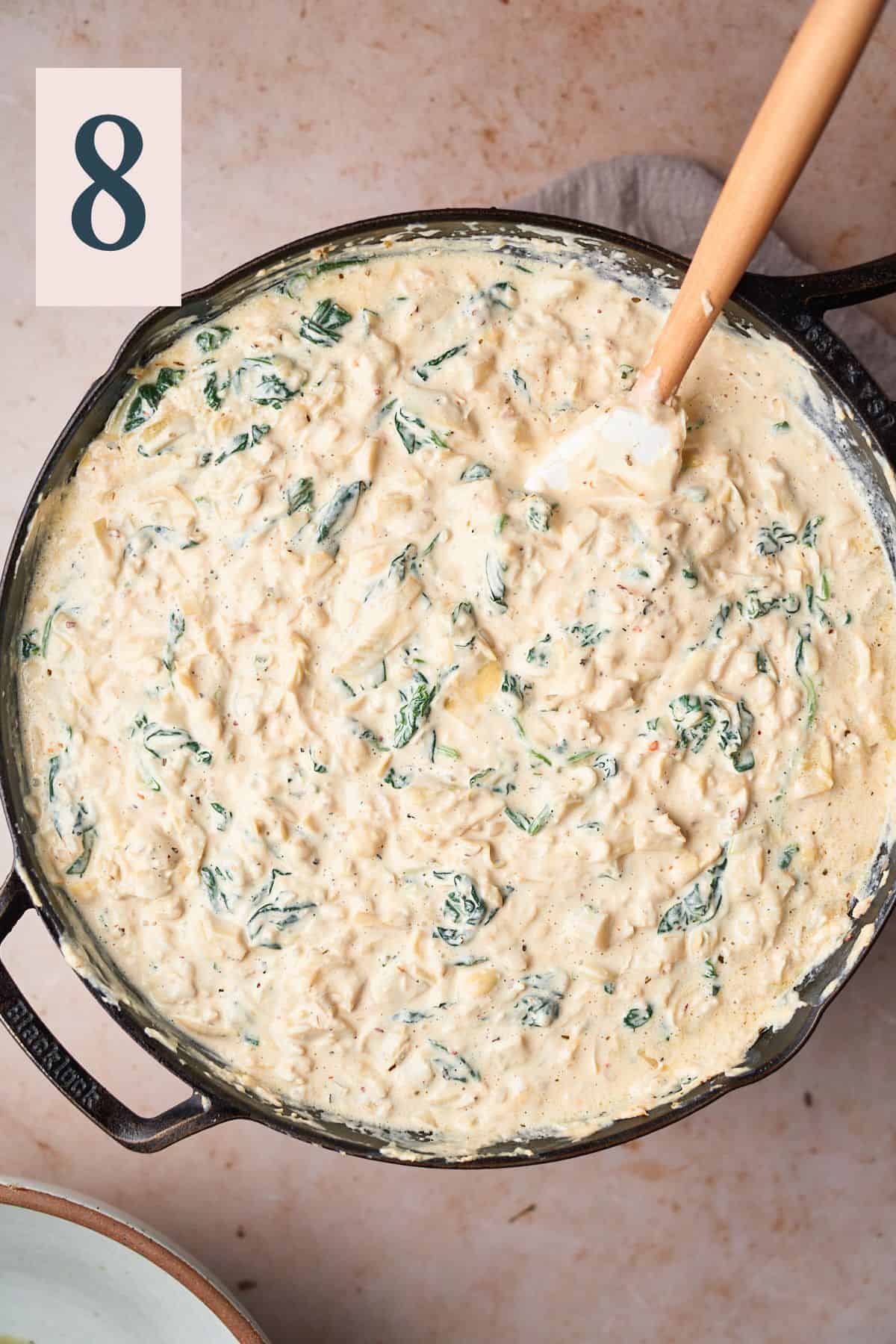 smooth and creamy mixture of spinach and artichoke dip with cheese added in a skillet. 