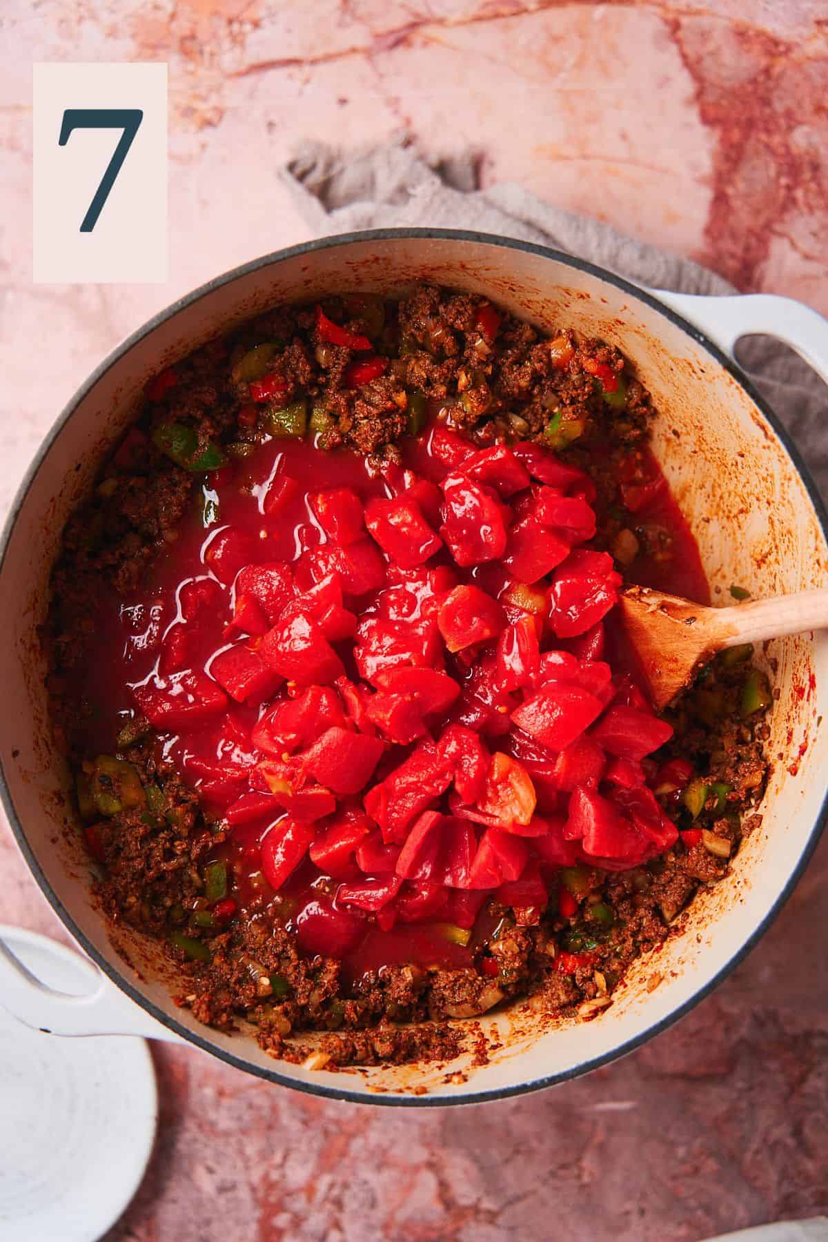 tomatoes added to a pot of ground beef.