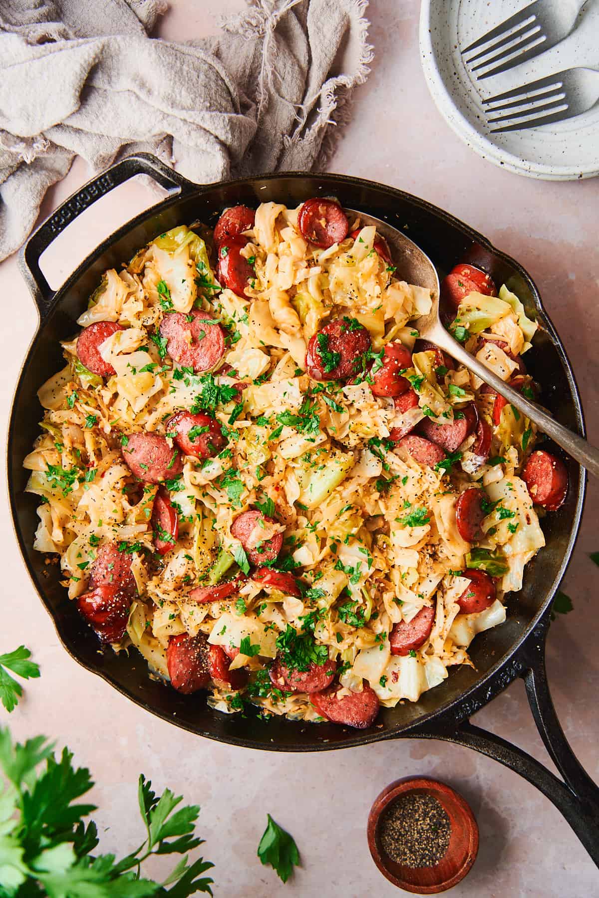 Cabbage and sausage recipe in a cast iron skillet on a warm backdrop.