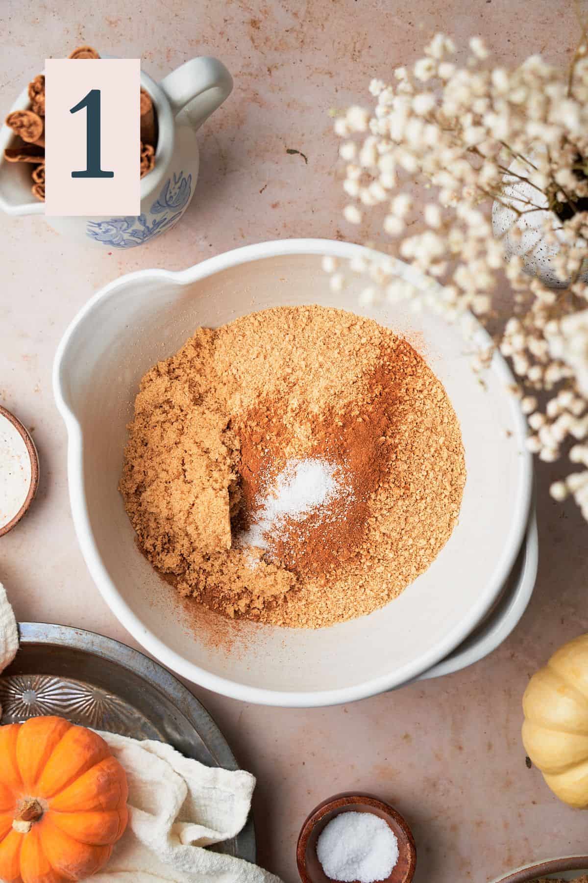 graham cracker crumbs in a mixing bowl with salt, cinnamon, pumpkin pie spice, and brown sugar. 
