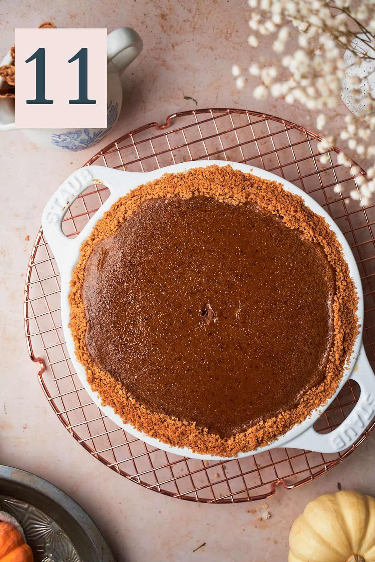 baked pumpkin pie on a cooling rack that has deepened in color significantly.
