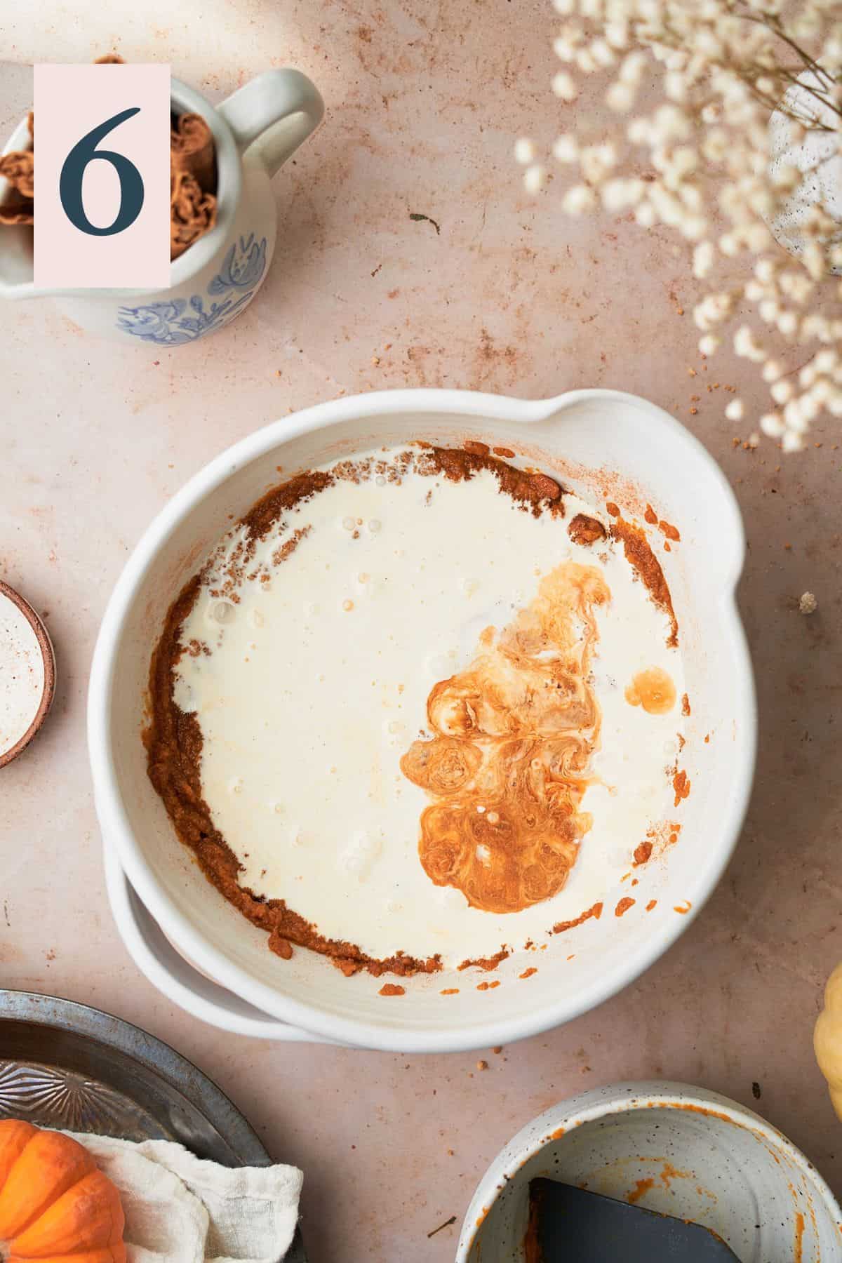 heavy cream and vanilla extract added to a mixing bowl with a pumpkin puree mixture. 