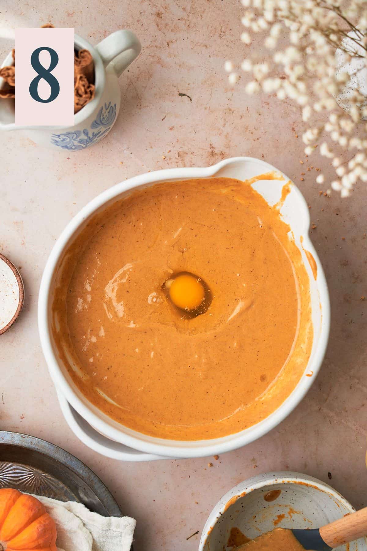 pumpkin pie mixture in a bowl with a raw egg inside. 