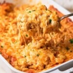 Delicious gooey southern baked mac and cheese being pulled up by a spoon from a casserole.