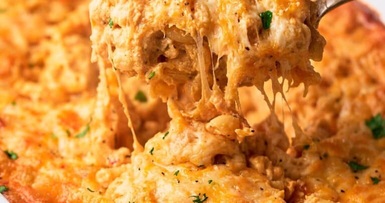 Delicious gooey southern baked mac and cheese being pulled up by a spoon from a casserole.