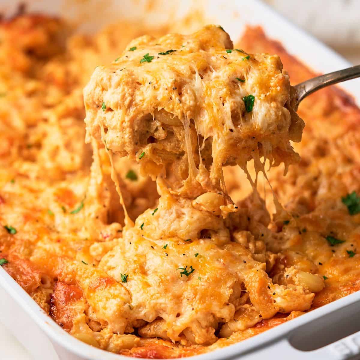 Delicious gooey southern baked mac and cheese being pulled up by a spoon from a casserole.