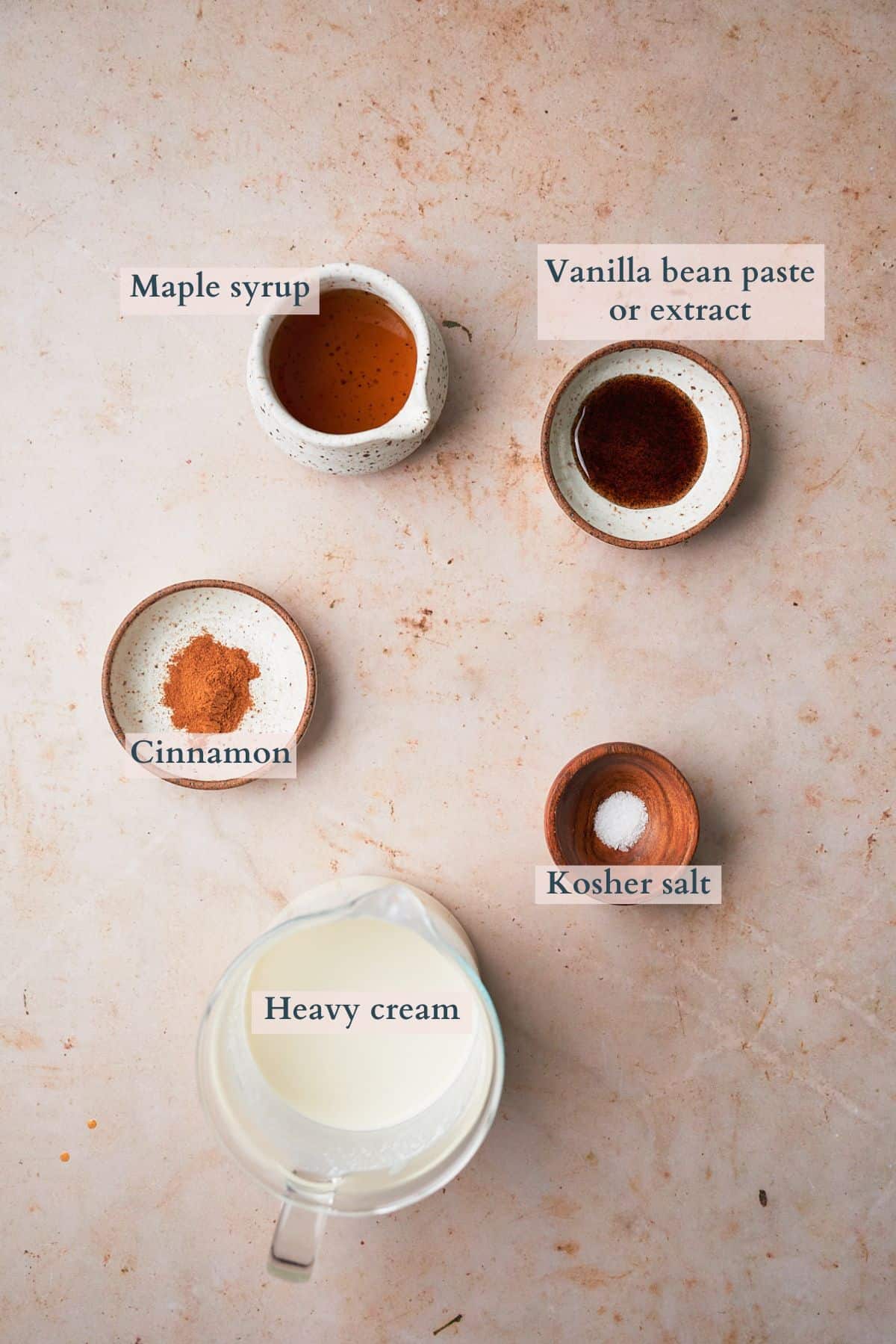 ingredients to make a spiced maple whipped cream topping laid out and labeled to denote each ingredient. 