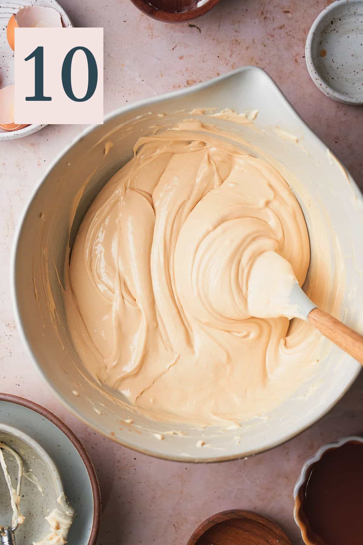 smooth and creamy caramel cheesecake batter in a mixing bowl with a rubber spatula. 