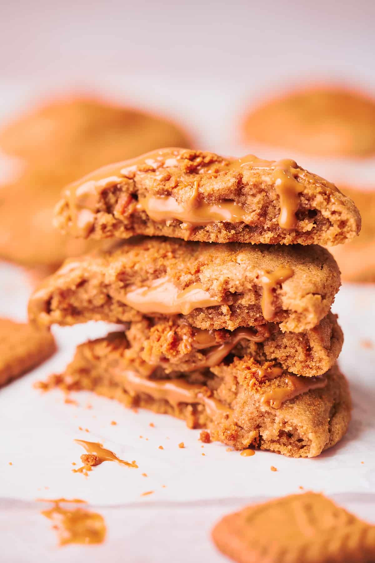 stack of cookies showing the center of the cookie to reveal the ooey-gooey Biscoff cookie butter filled center with the cookie butter oozing and melting out from the center of the cookie. 