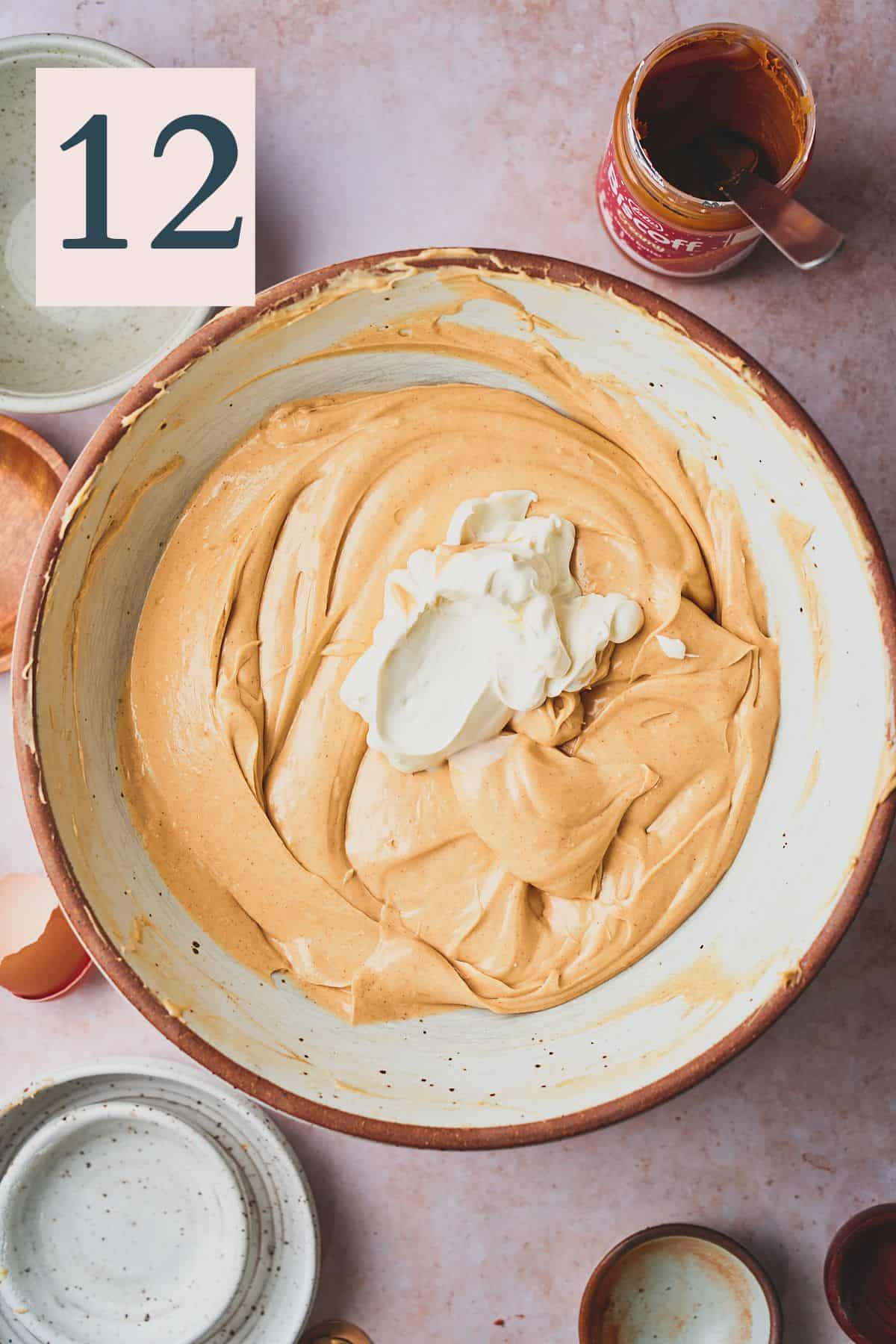 Creamy cookie butter cheesecake batter in a large bowl with sour cream.