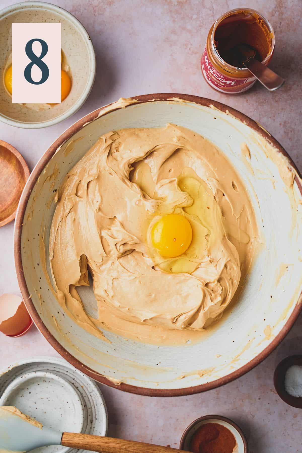 creamy biscoff cookie butter cheesecake batter in a bowl with an egg added. 