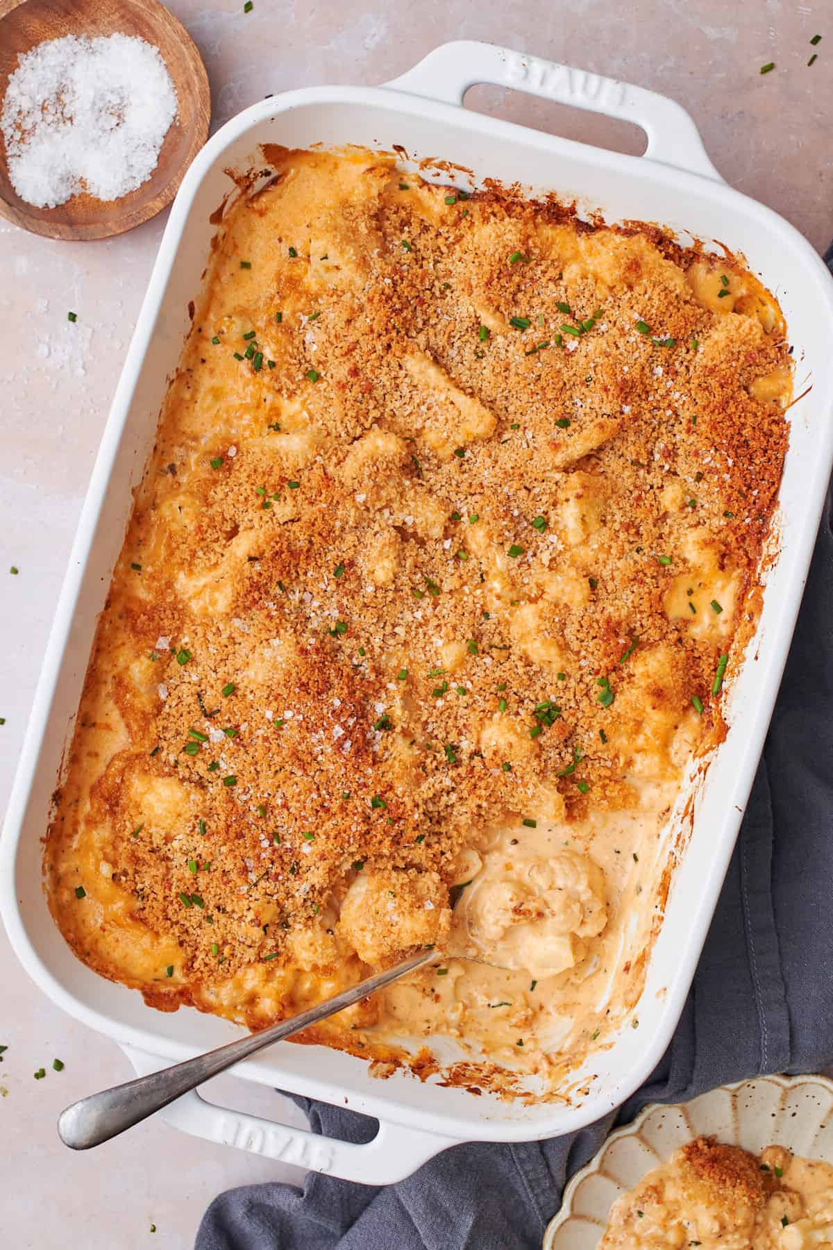 casserole dish of baked cheesy cauliflower with a spoonful taken out from the corner.