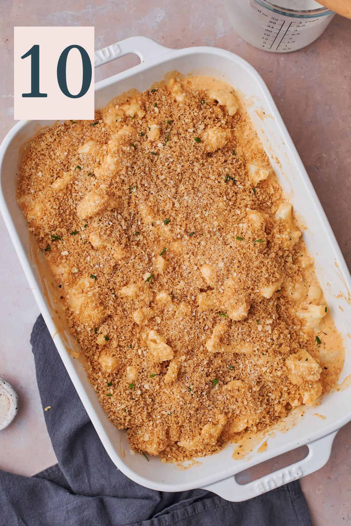 breadcrumbs sprinkled overtop of cauliflower in a cheesy sauce in a casserole dish. 
