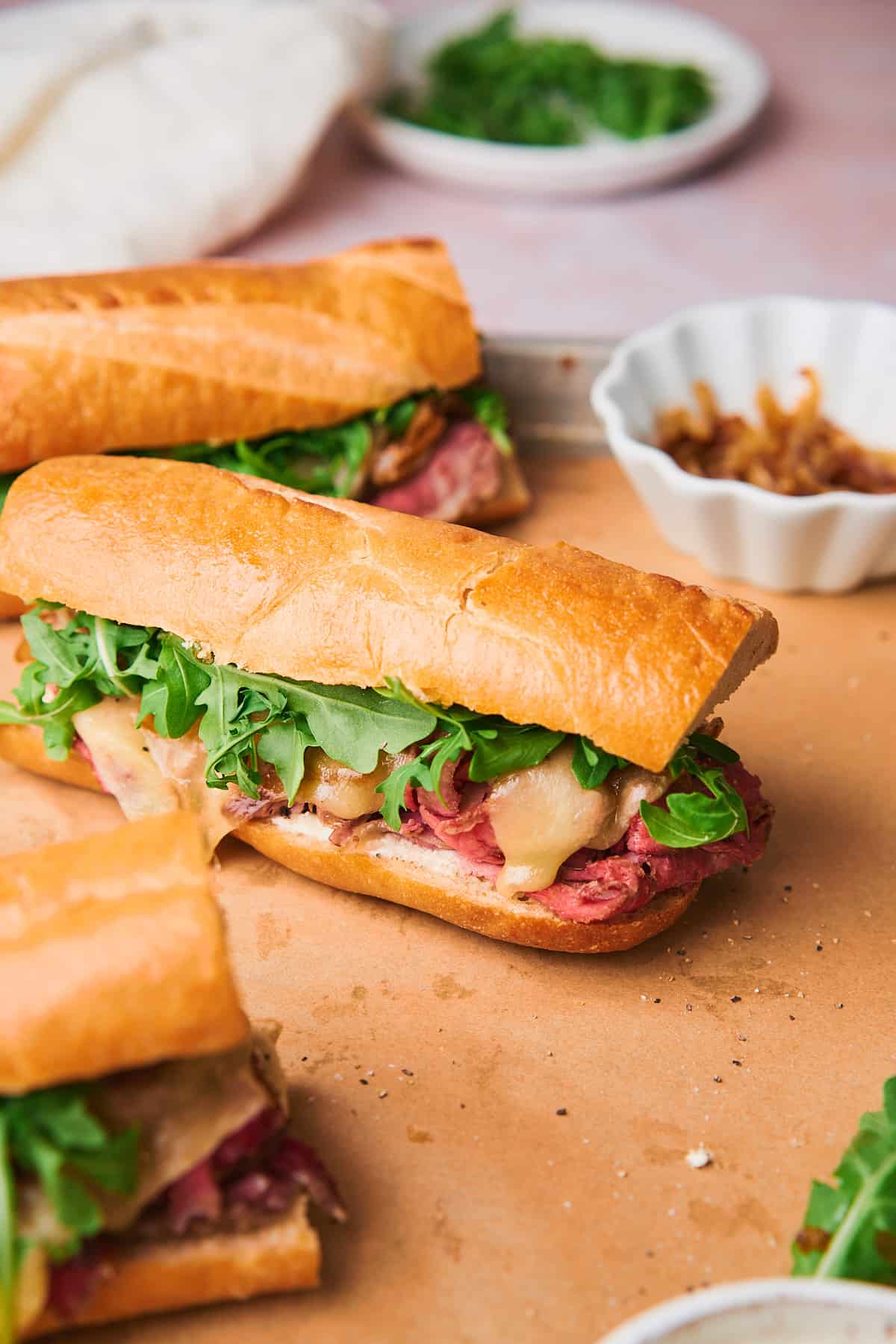 Delicious prime rib sandwich with caramelized onions, arugula, creamy horseradish sauce, and provolone cheese on a baguette.