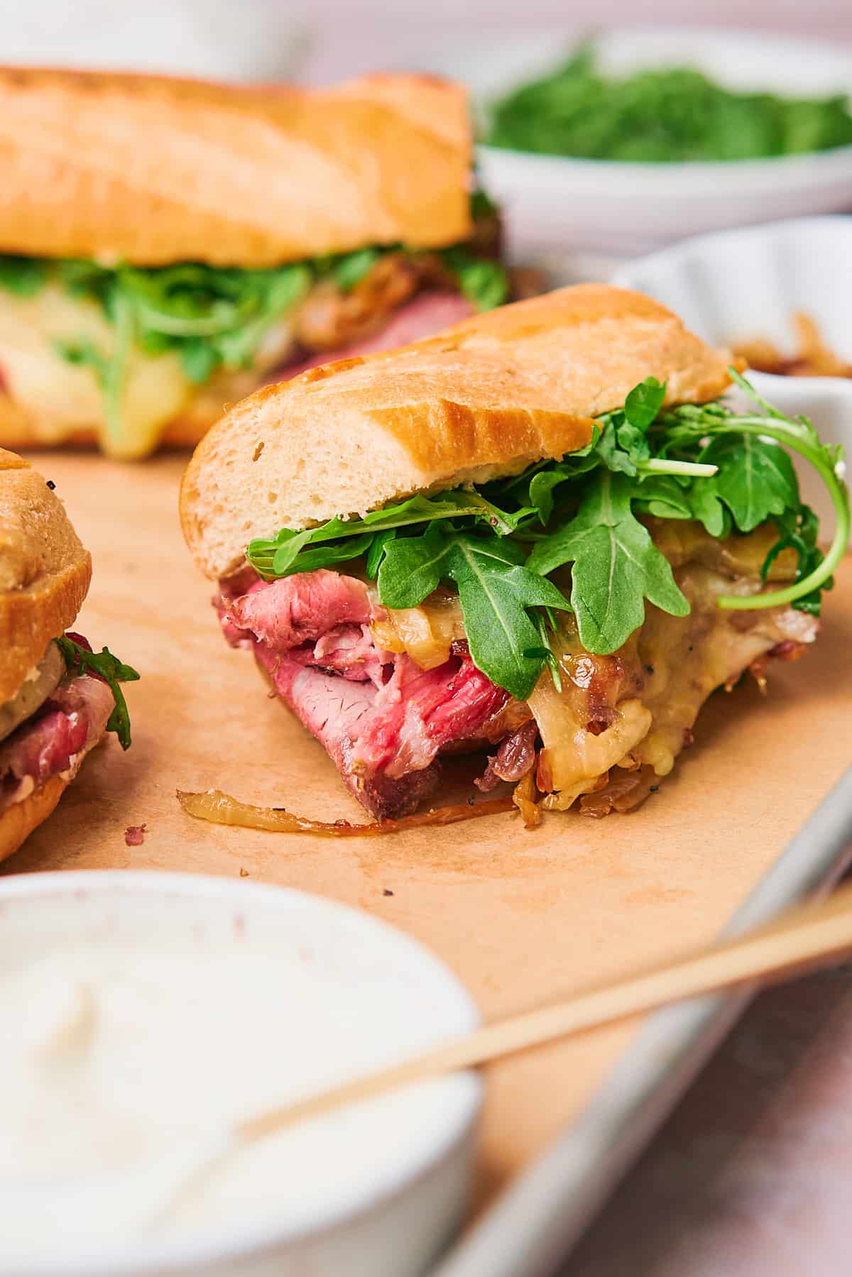 straight on shot of a prime rib sandwich with caramelized onions, arugula, and provolone cheese. 