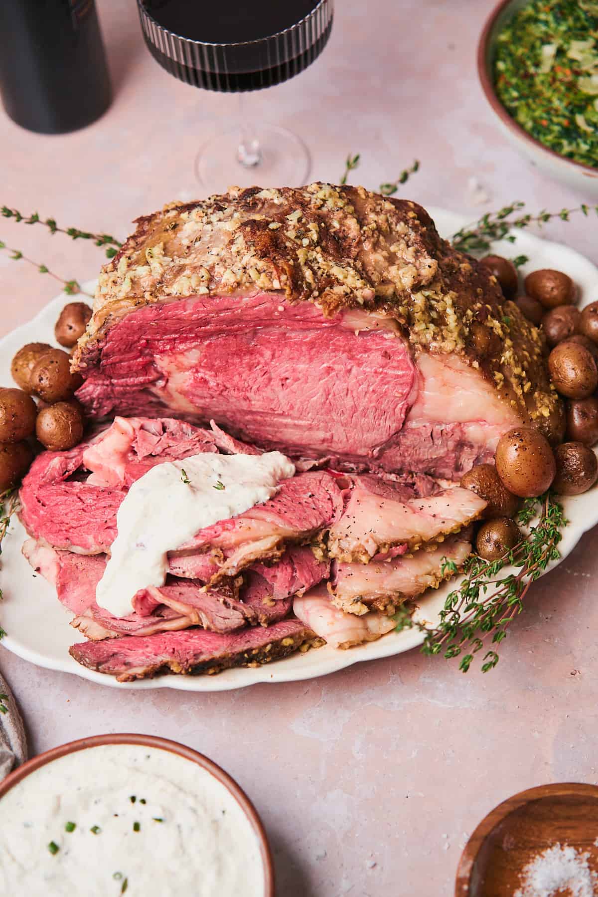 Cooked prime rib on plate and with some thin slices cut away from the roast, with creamy horseradish sauce covering the slices. 