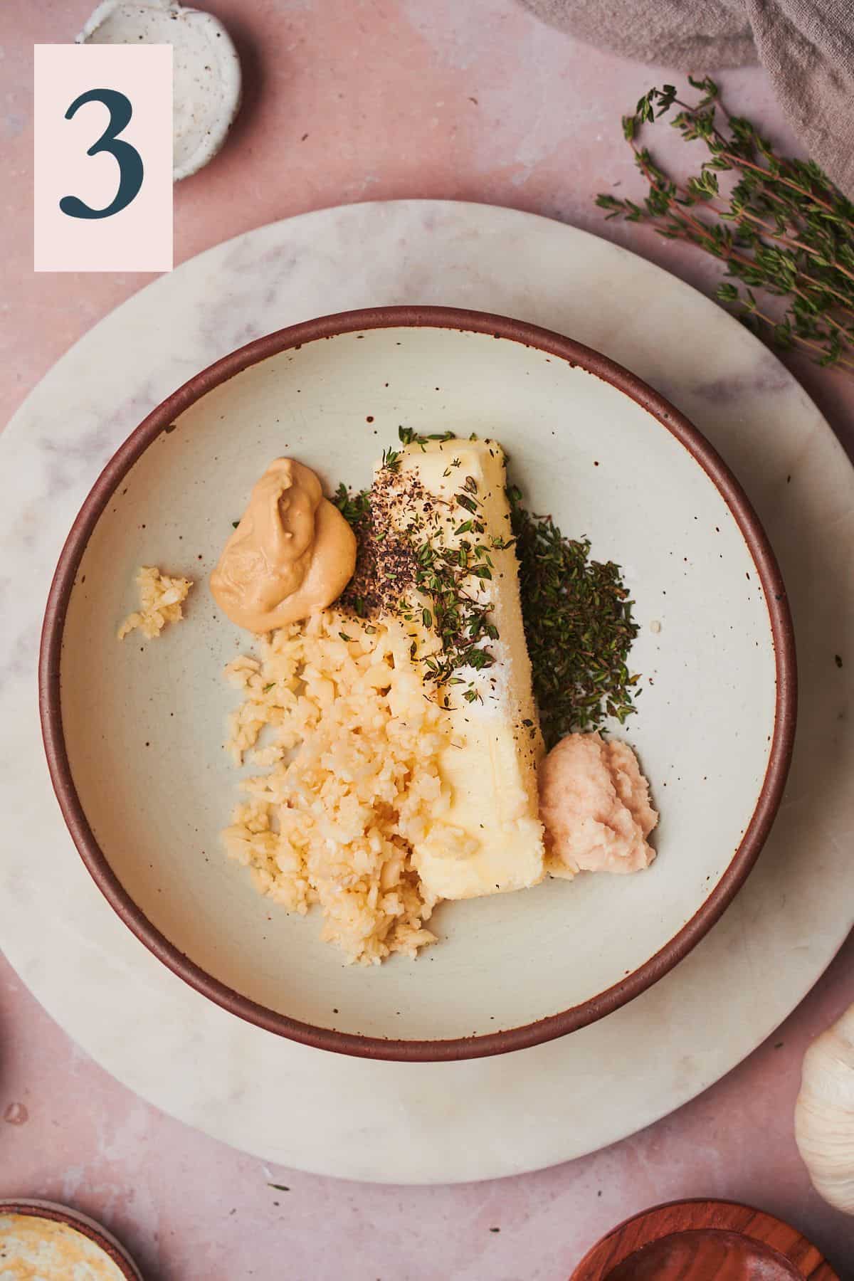 stick of butter in a bowl with thyme, salt, dijon mustard, pepper, and minced garlic. 