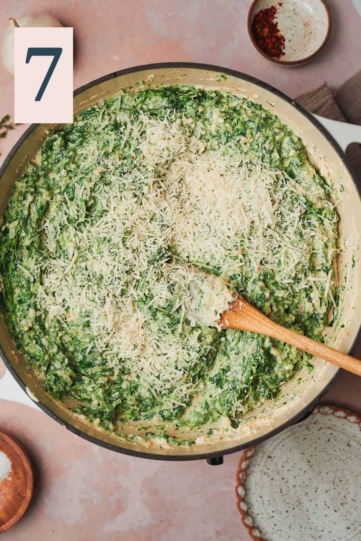 bright cream creamed spinach in a skillet with shredded parmesan cheese added to it. 