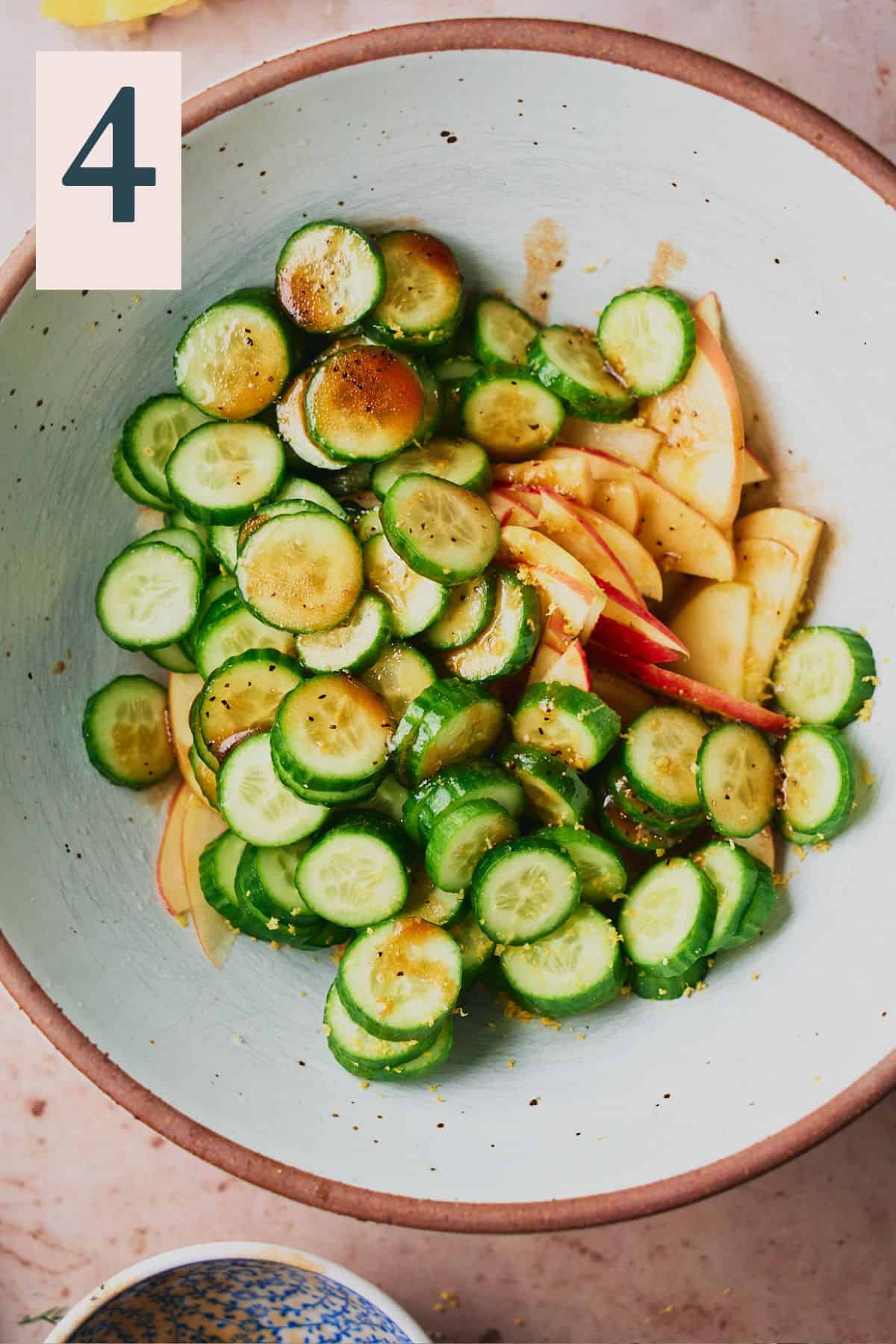 apples and cucumbers in a large mixing bowl covered with a balsamic dressing.