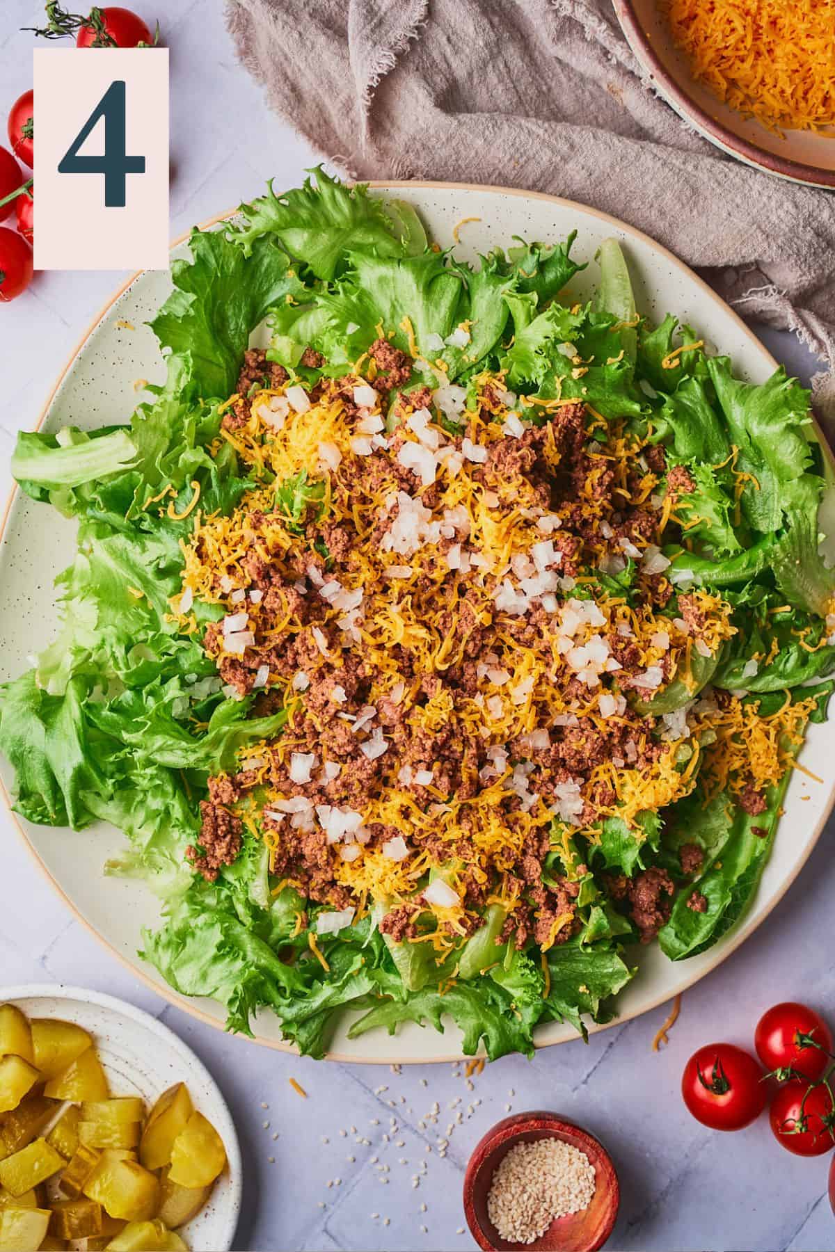 bed of lettuce topped with cooked ground beef, onions, and cheese.