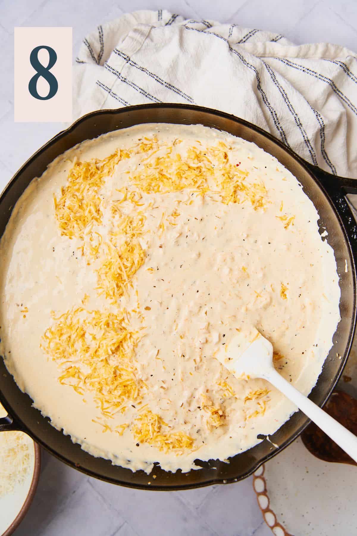 cheese added to a creamy sauce in a skillet. 