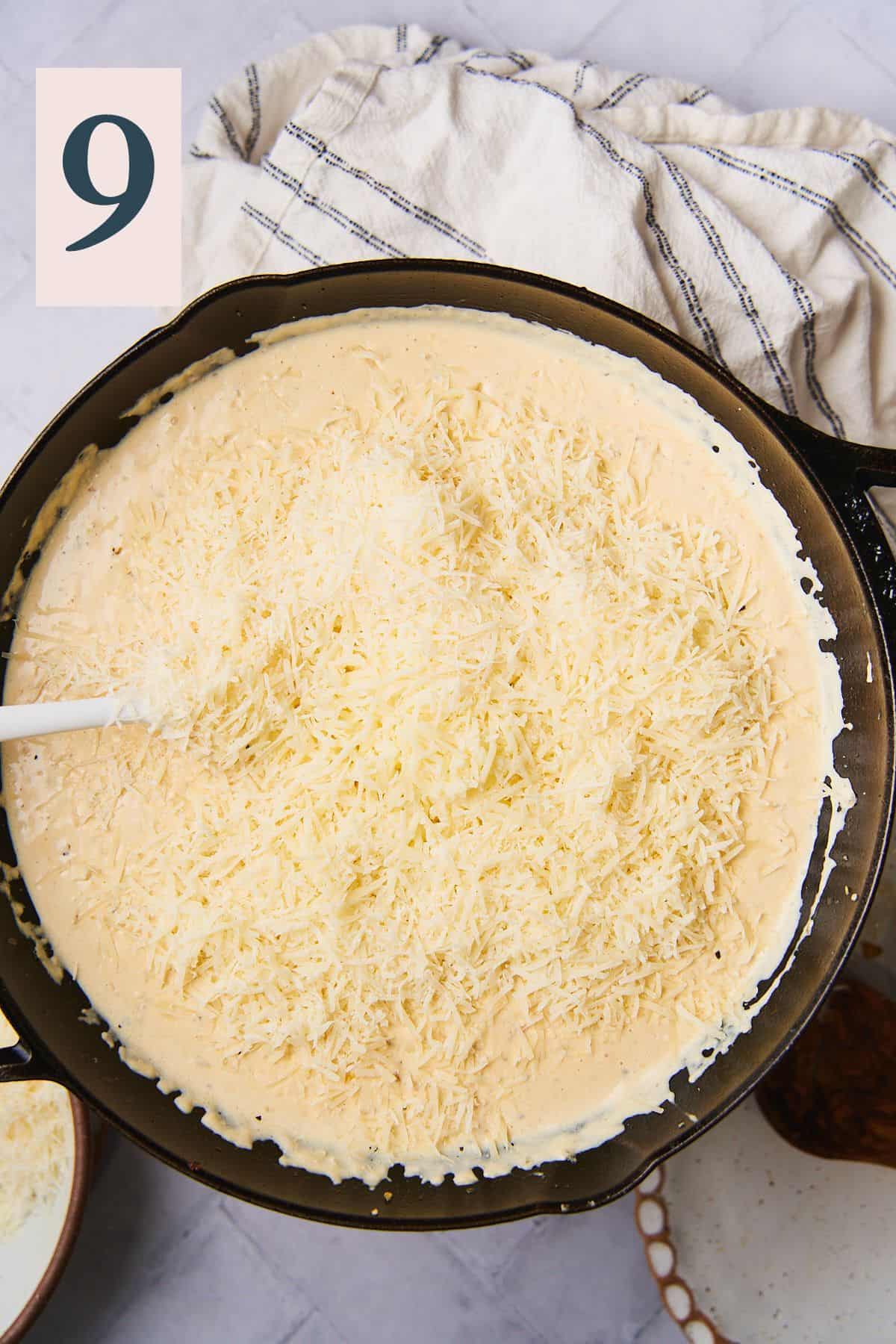 more cheese added to a creamy sauce in a skillet. 