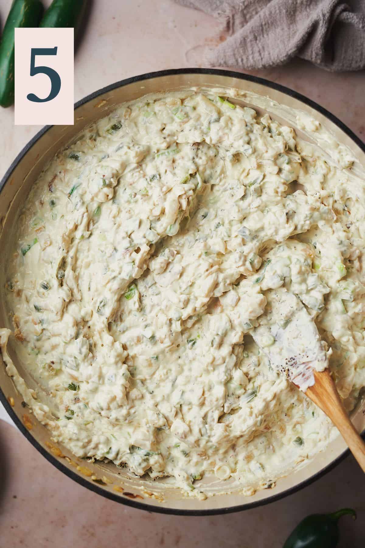 creamy jalapeno dip in a skillet with a rubber spatula. 