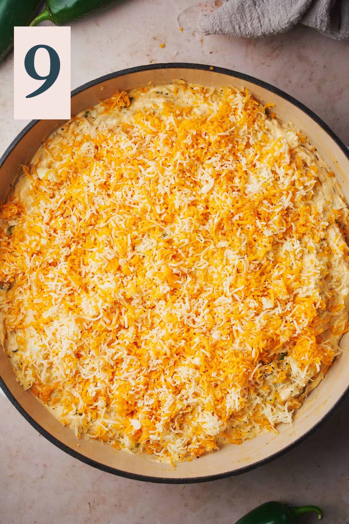 skillet covered with shredded cheese over top of a cream cheese mixture. 