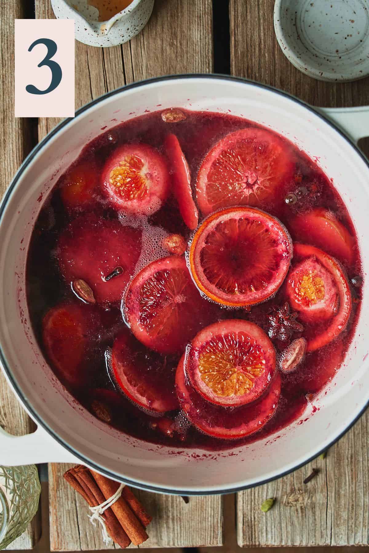 Mulled fruit, spices, and red wine in a dutch oven. 