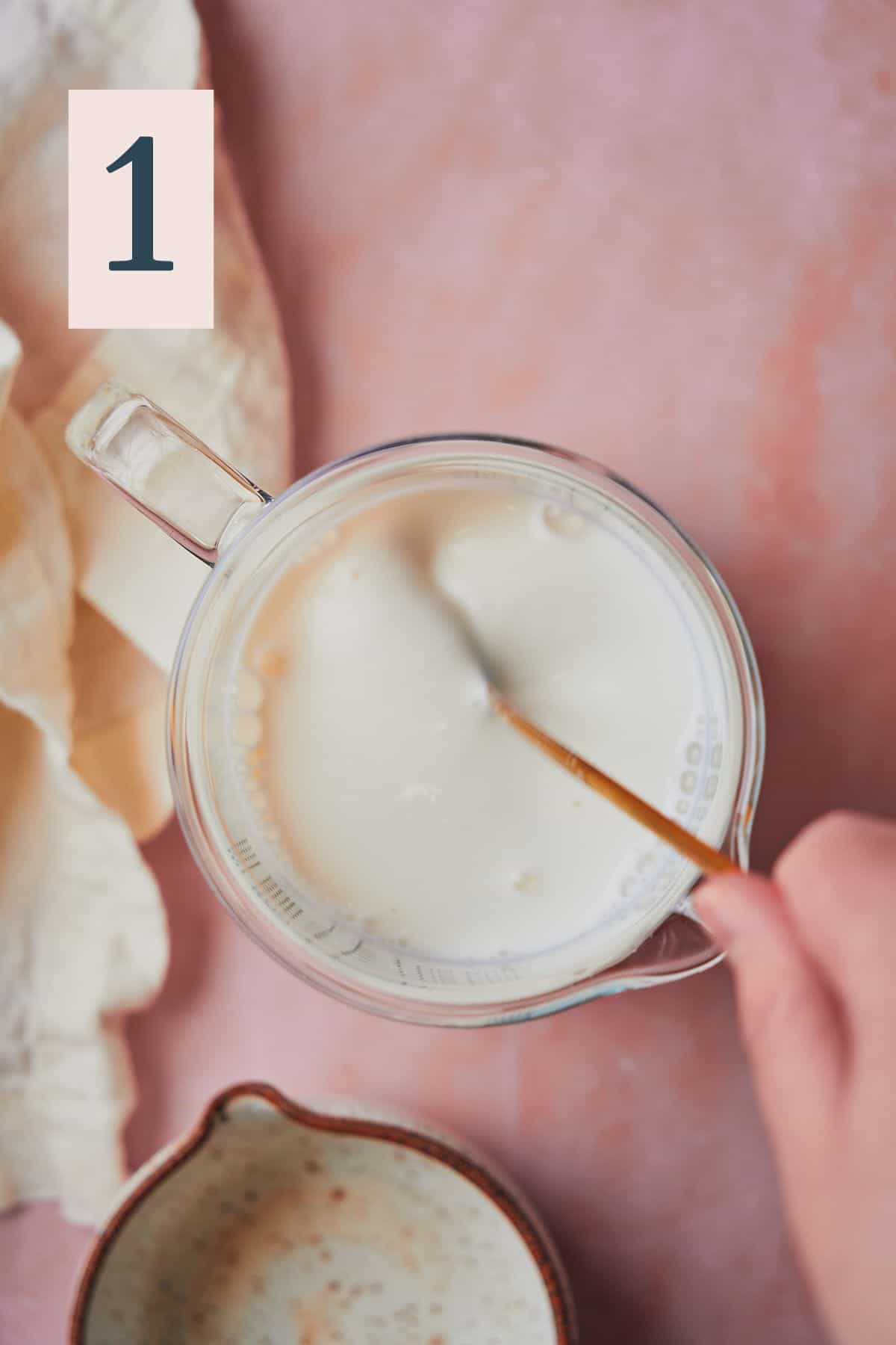 hand making a homemade buttermilk mixture in a beaker.