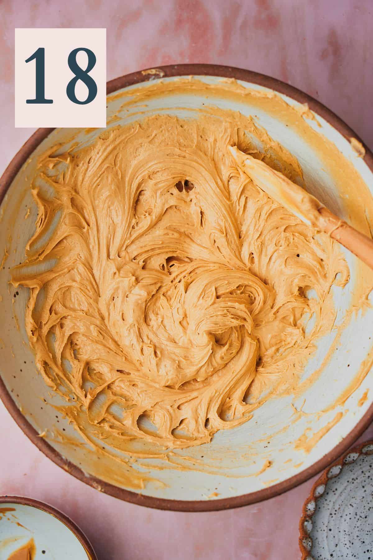 creamy cream cheese peanut butter frosting in a large bowl with a rubber spatula. 