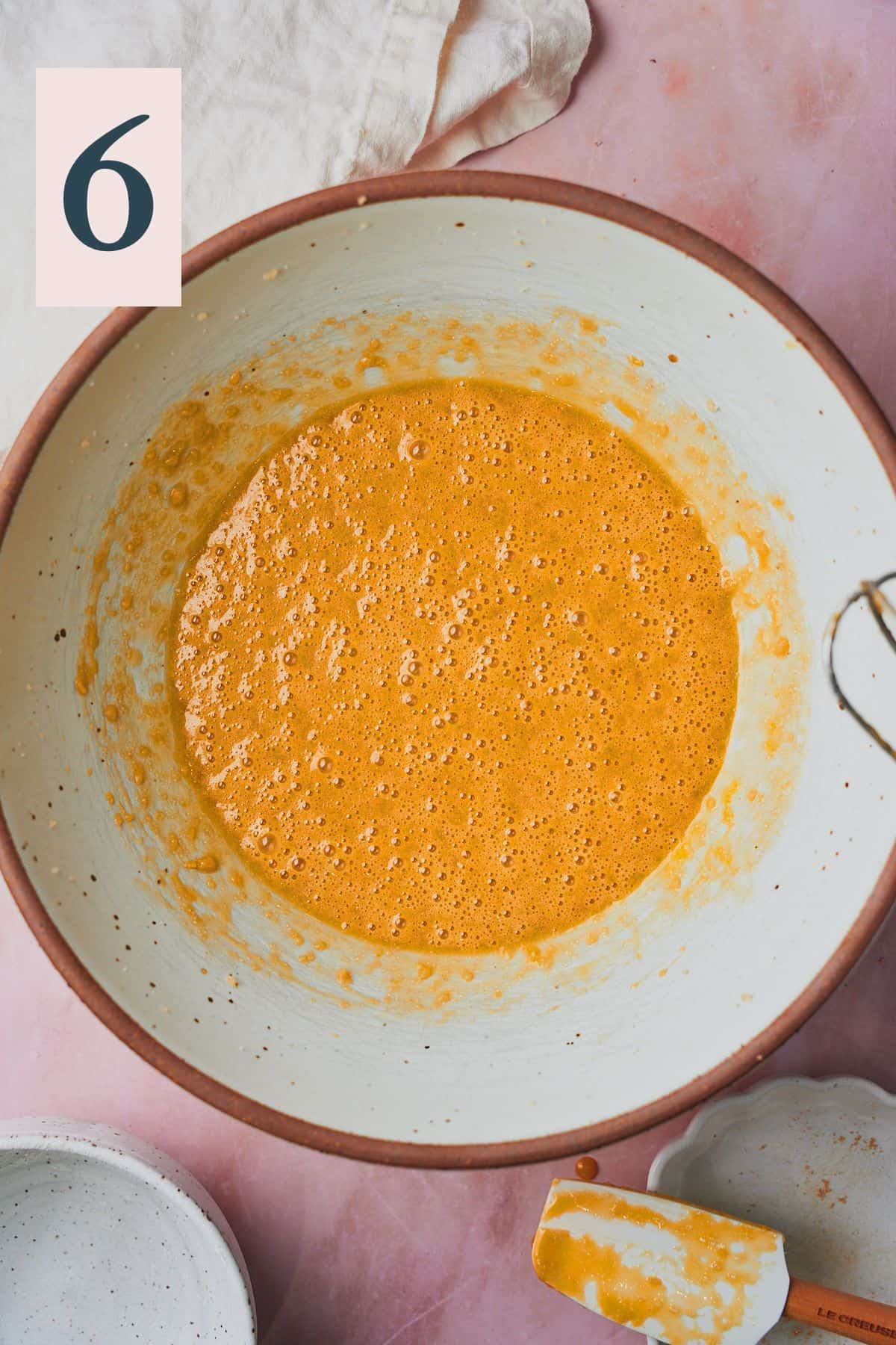 yellow-ish orange batter for banana cake beginning to form in a large bowl.