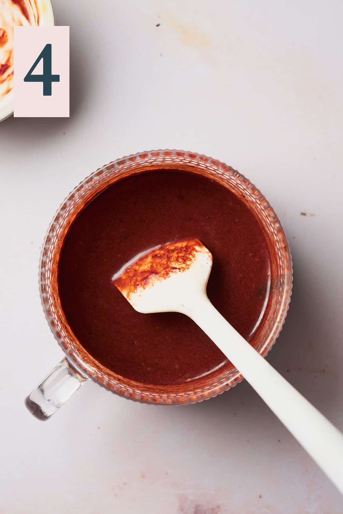 Smooth chocolate mixture with a small rubber spatula inside of a mug. 