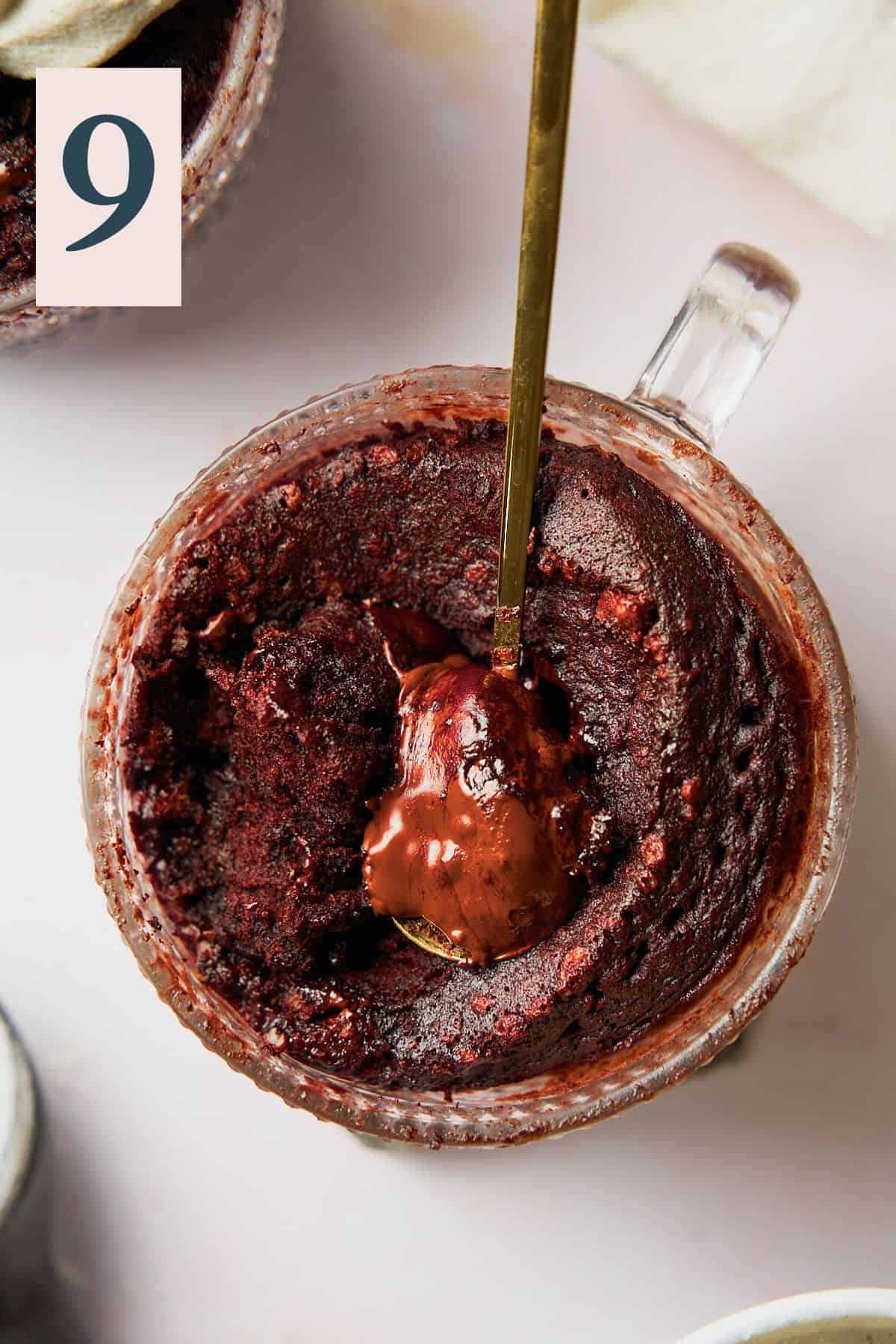 A spoon dug inside of a chocolate mug cake to reveal the melty chocolate center. 