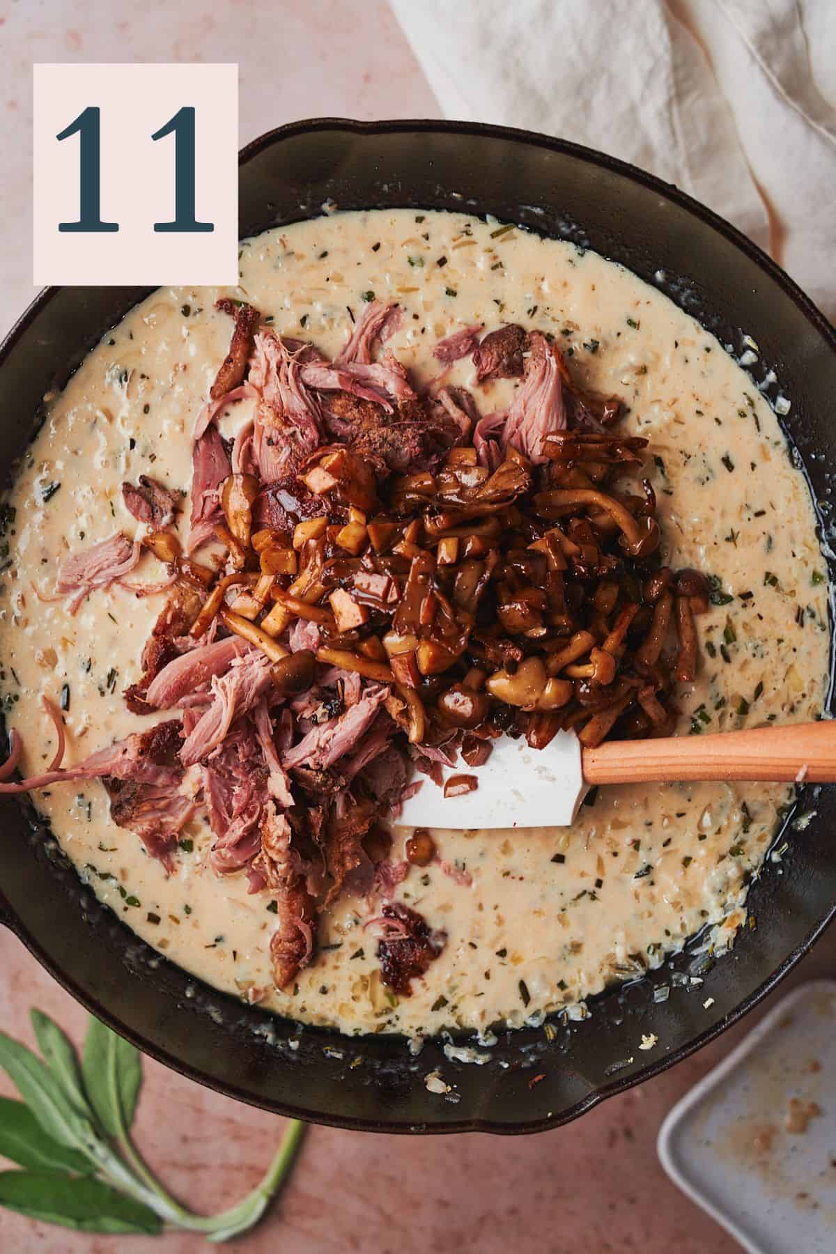 Duck and mushrooms added to a creamy sauce in a skillet. 