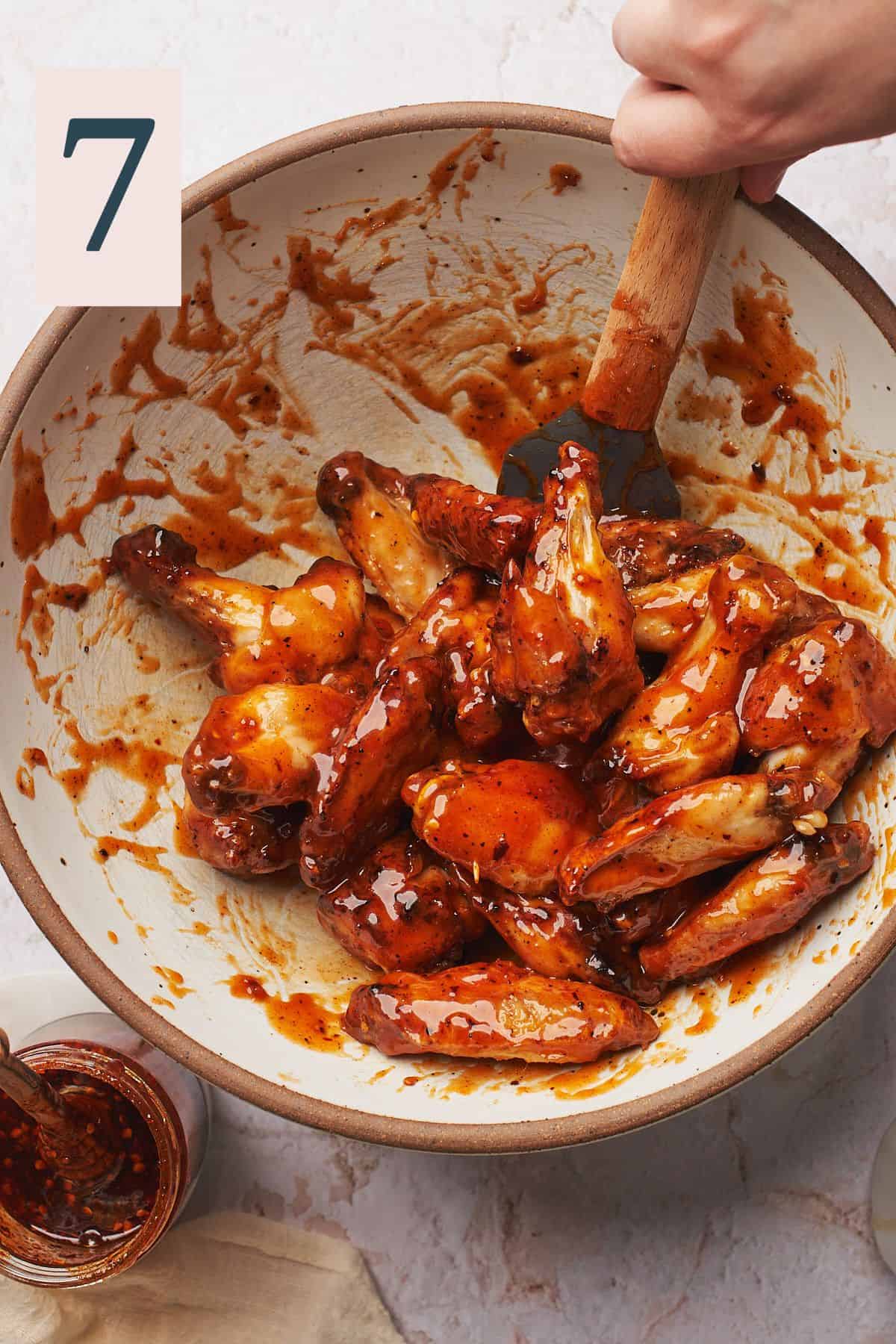 chicken wings in a large bowl coated with hot honey sauce.