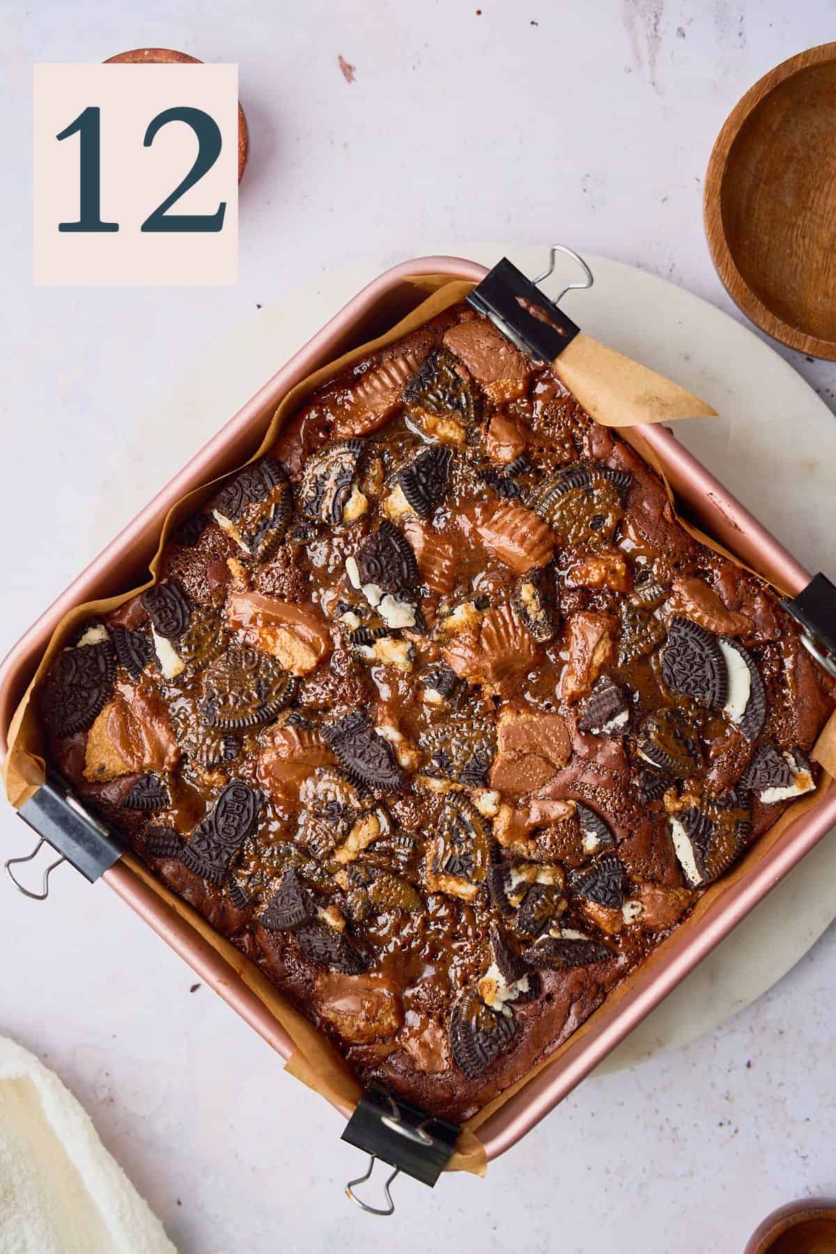 Baked loaded brownies in a pan with reese's, oreos, and salted caramel. 