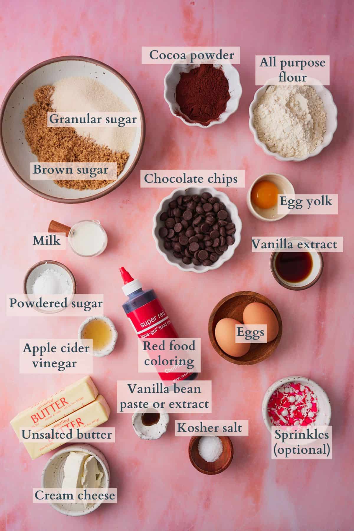 Red velvet brownies ingredients graphic with ingredients laid out on a pink backdrop in small bowls and labeled to denote each ingredient.