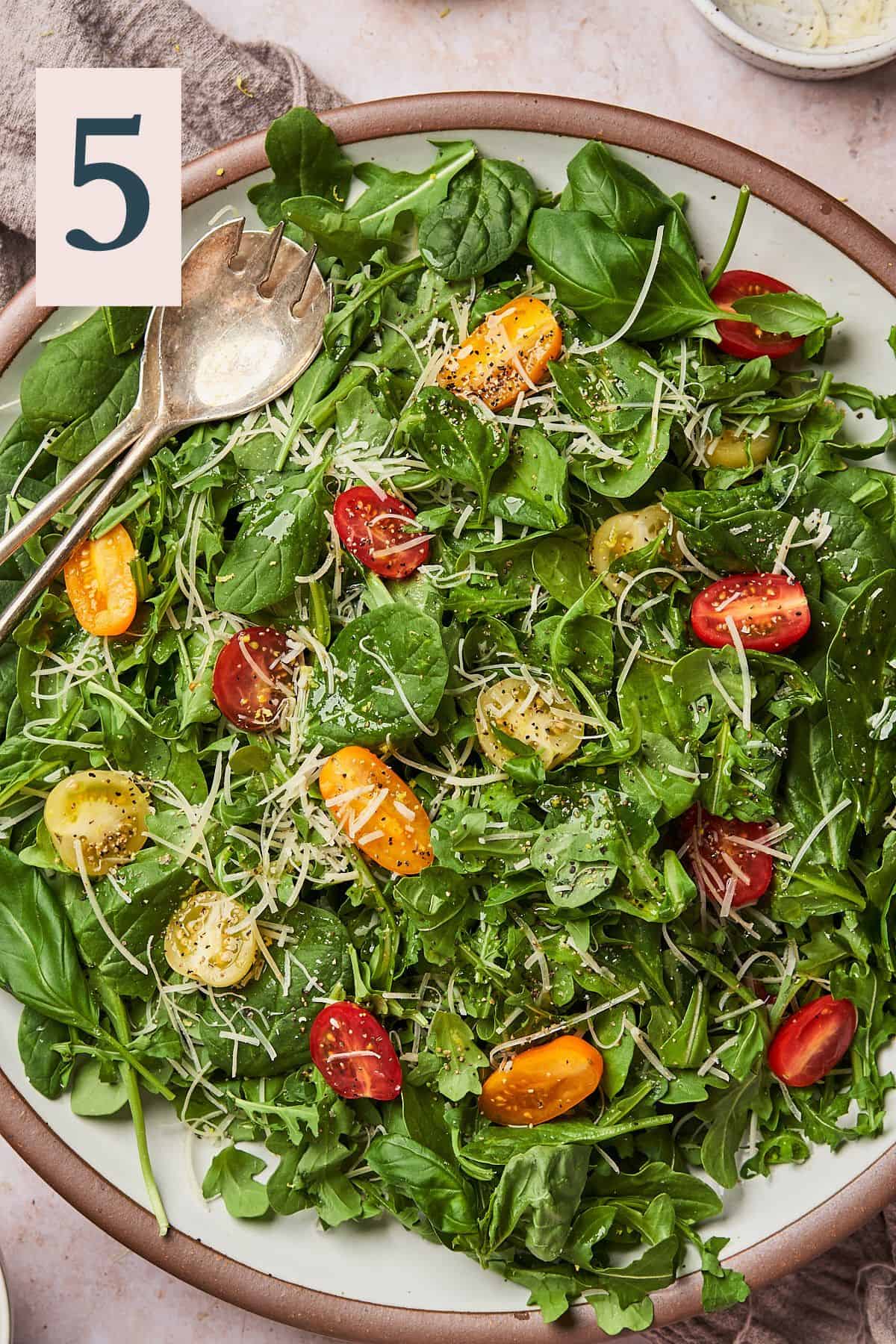 close up zoomed in shot of an arugula spinach salad with tomatoes.