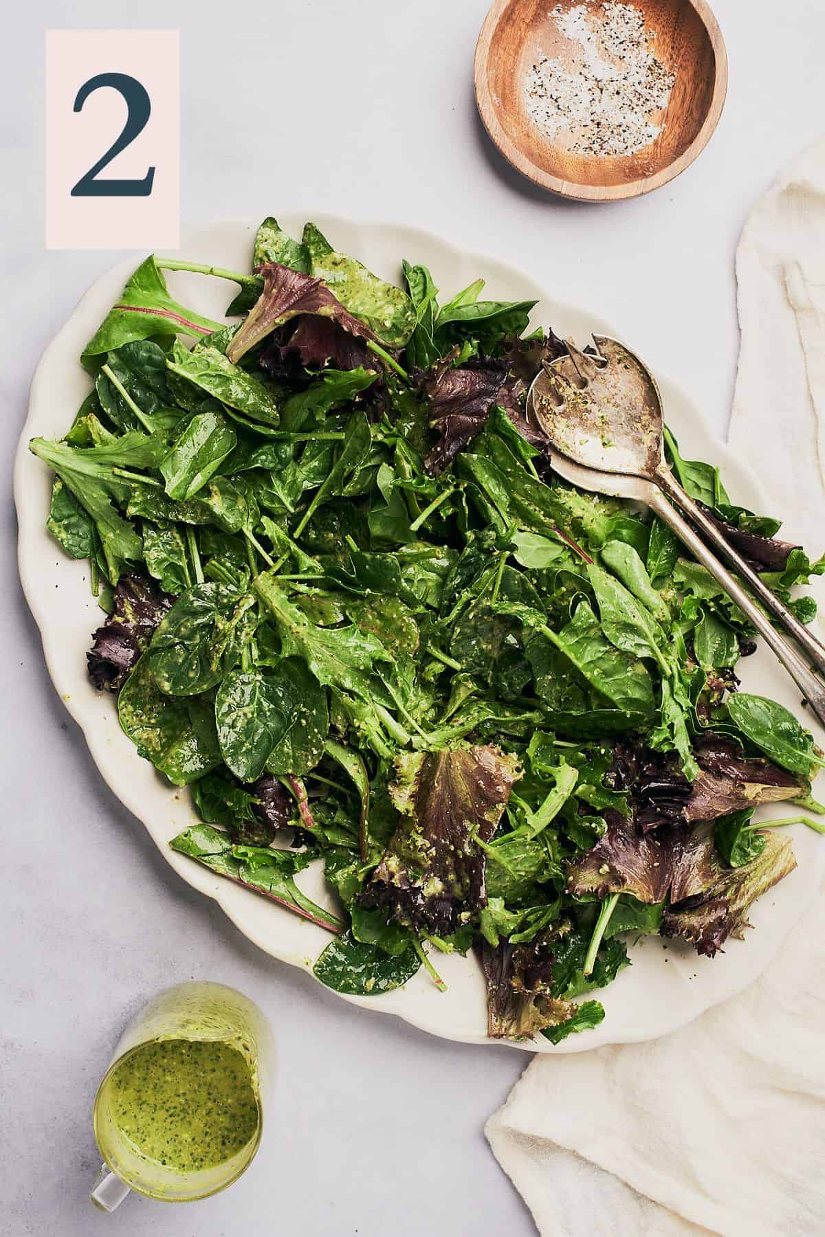 leafy greens dressed with a little salt and pepper on a large serving platter.
