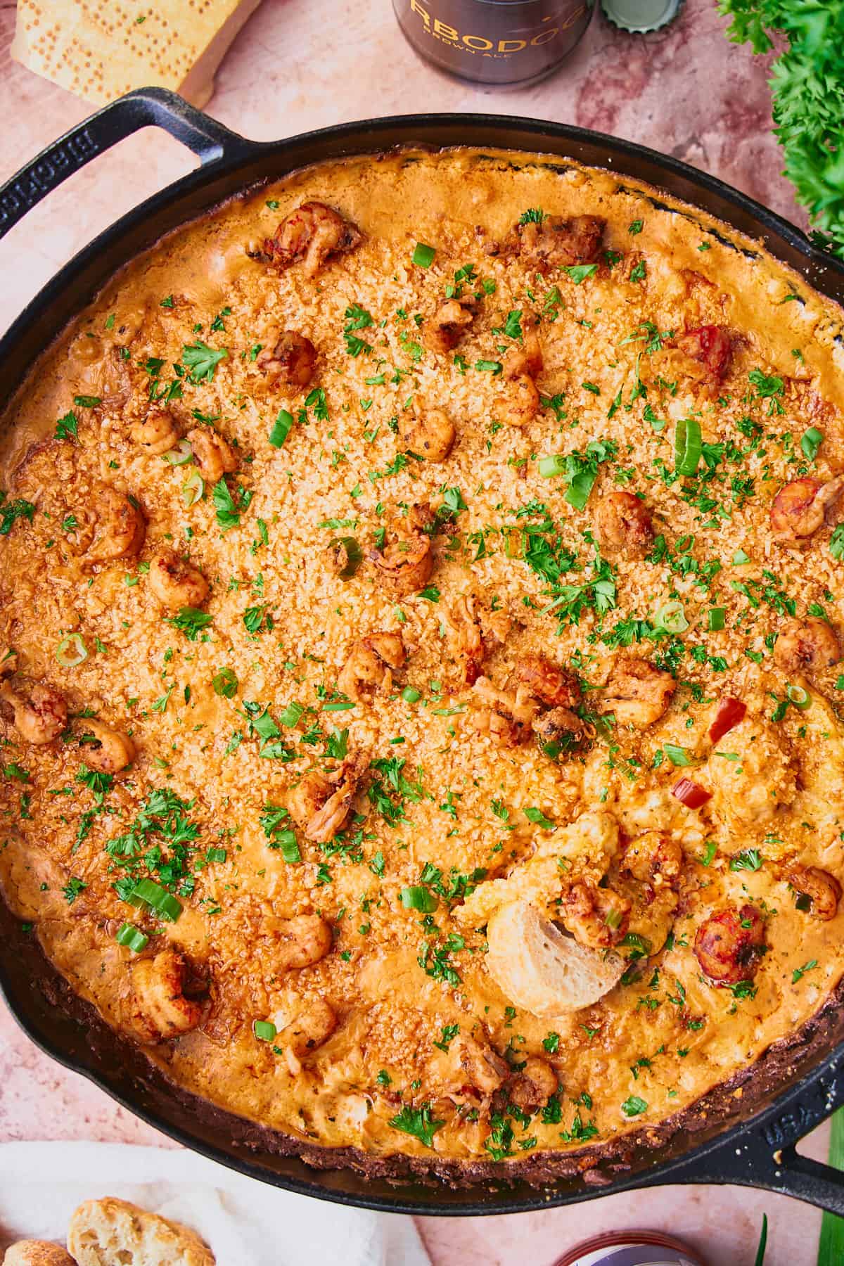 Cheesy and gooey crawfish dip topped with pieces of crawfish with a piece of bread in the center. 