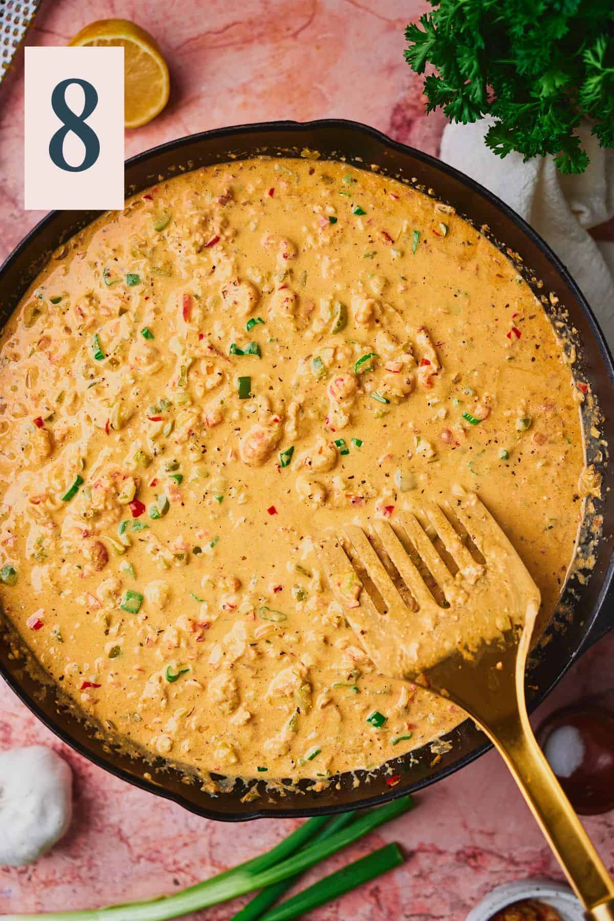 Smooth and creamy crawfish dip in a cast iron skillet with a spatula in the skillet.