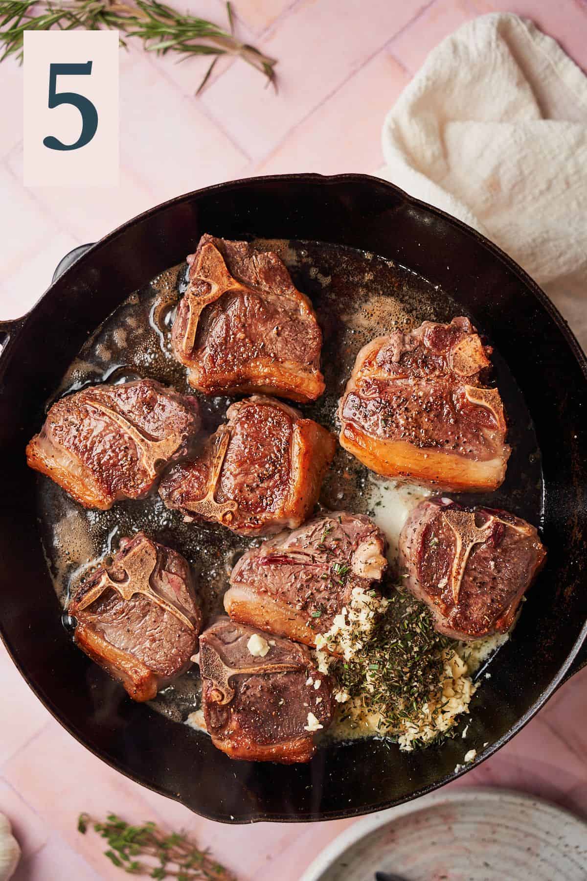 Cooked lamb chops in a large skillet with butter, herbs and garlic added.