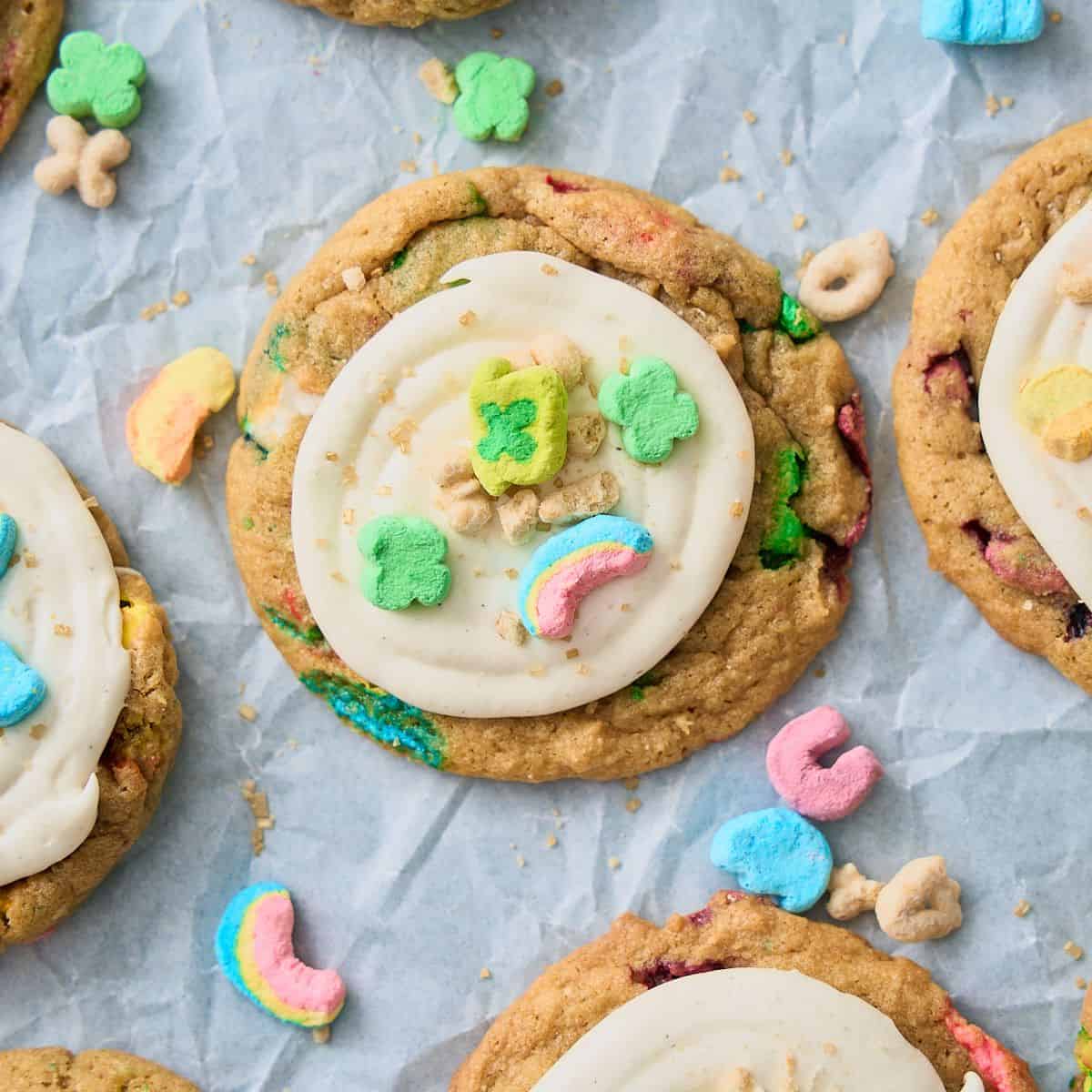 Close up shot of Lucky charms Cookies with a marshmallow fluff frosting and cereal pieces and marshmallows on top of the cookies.