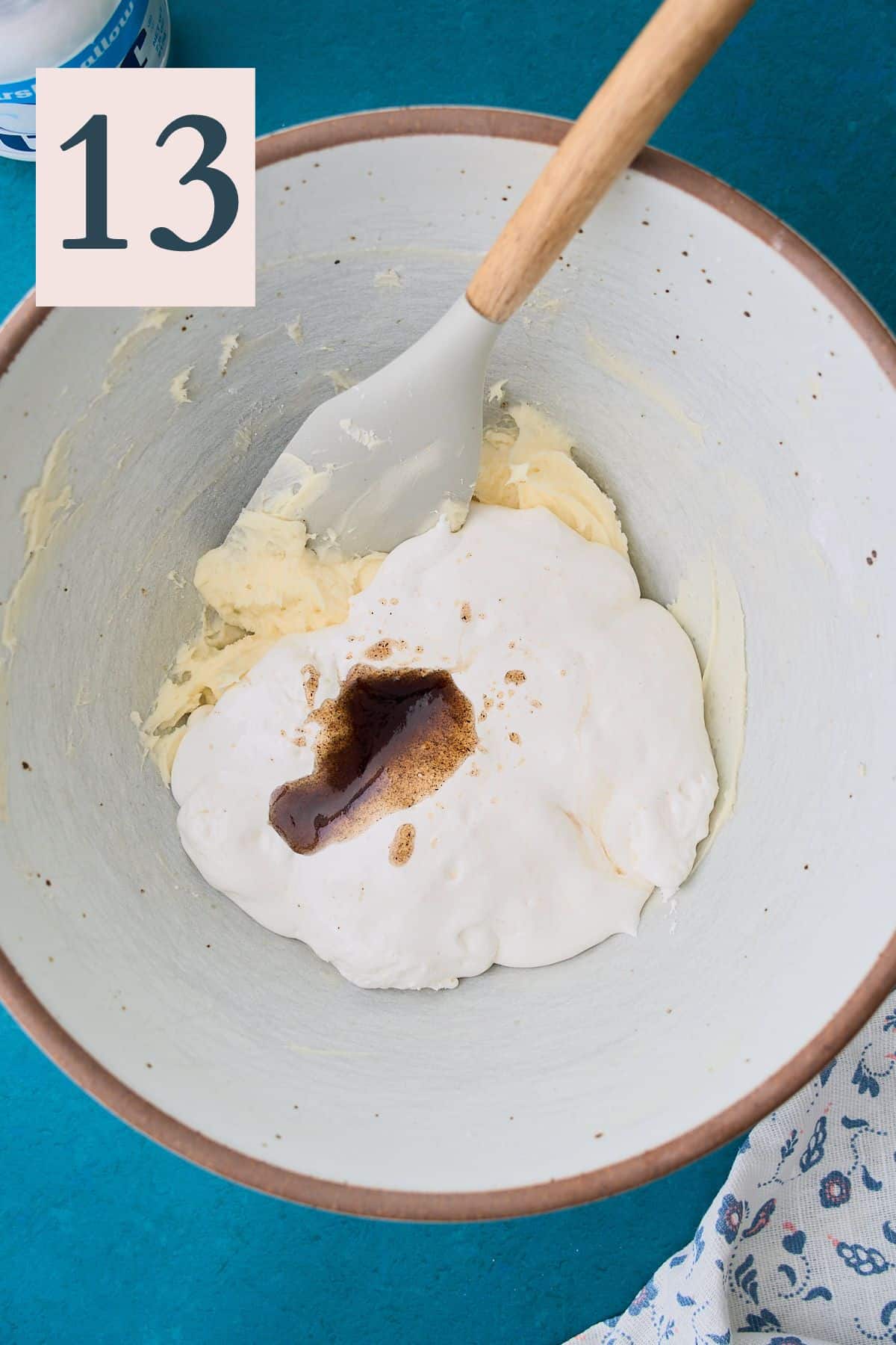Marshmallow fluff and vanilla bean extract added to a mixing bowl to make frosting.