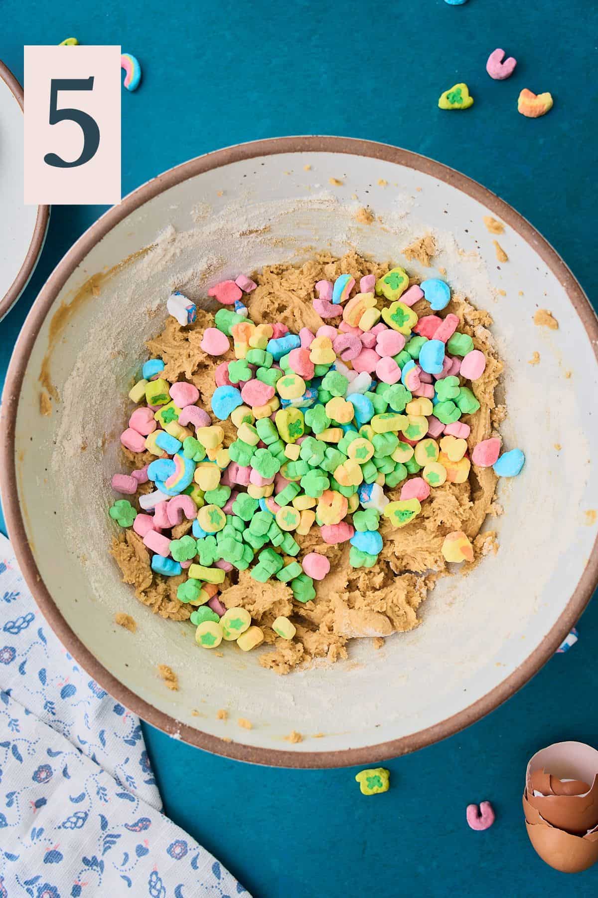 Lucky Charms marshmallows added to a bowl of cookie dough.