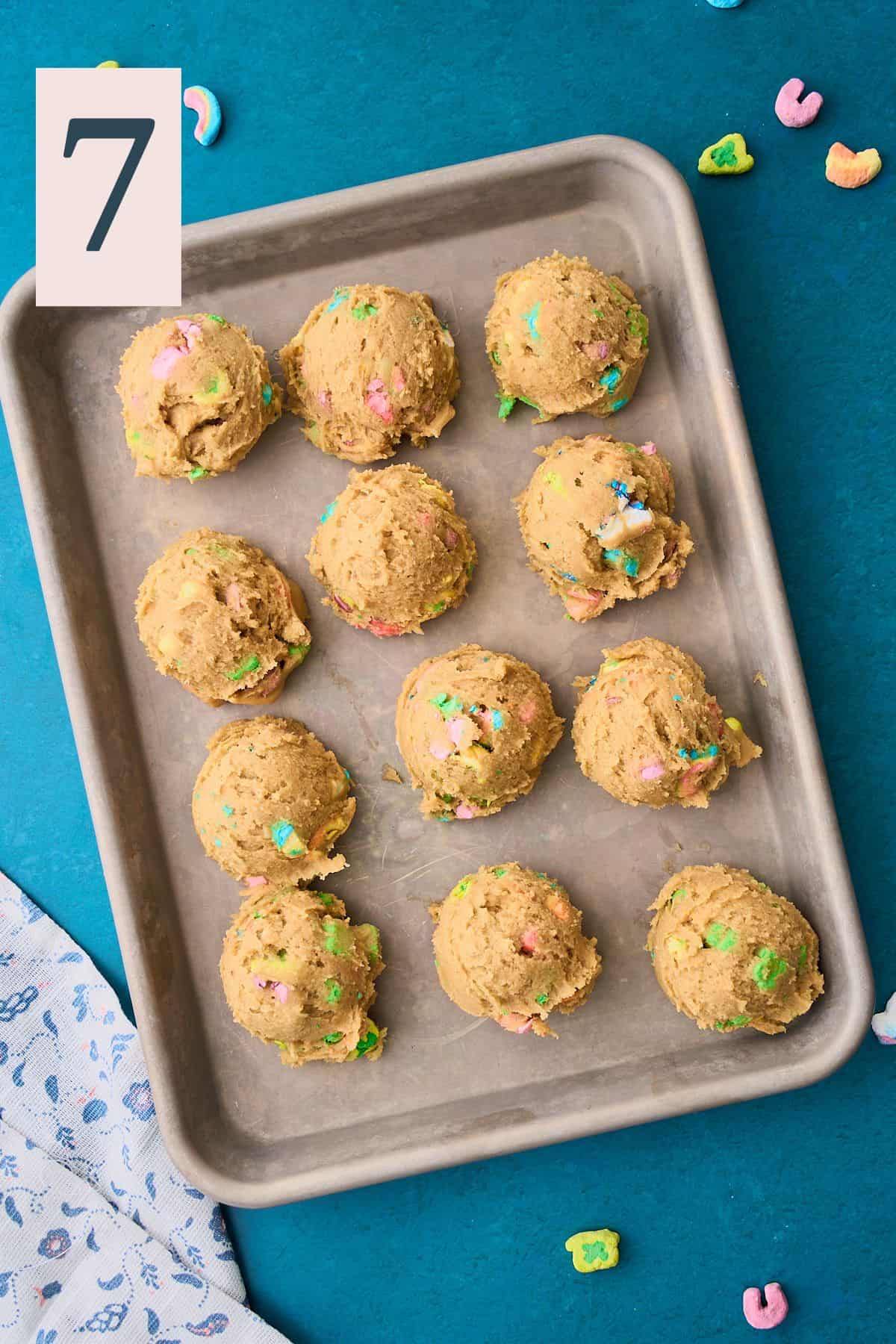 Balls of lucky charms cookie dough on a baking sheet. 