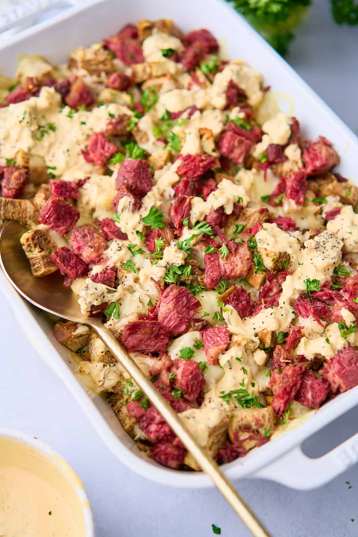 Close up shot of a reuben casserole in a dish with a spoon scooping into the casserole. 